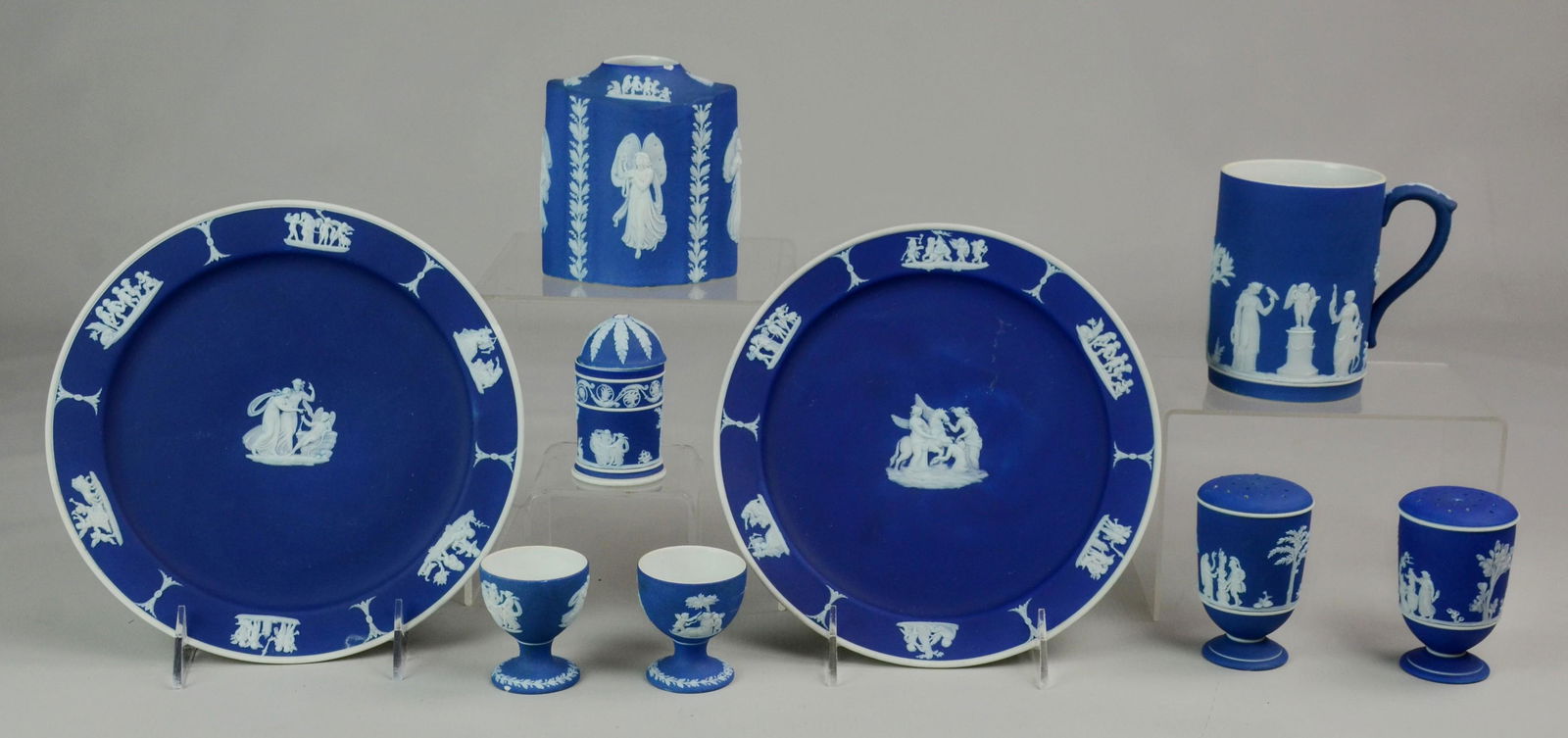 (9) Pcs Wedgwood Dark Blue Dip Jasperware: (9) Pcs Wedgwood Jasperware, cobalt dark blue dip, c/o 2 8-1/8" dia plates, 2 shakers, mug, 2 egg cups (one with crack), tea jar (missing lid, chip at neck), cylinder box (missing finial)