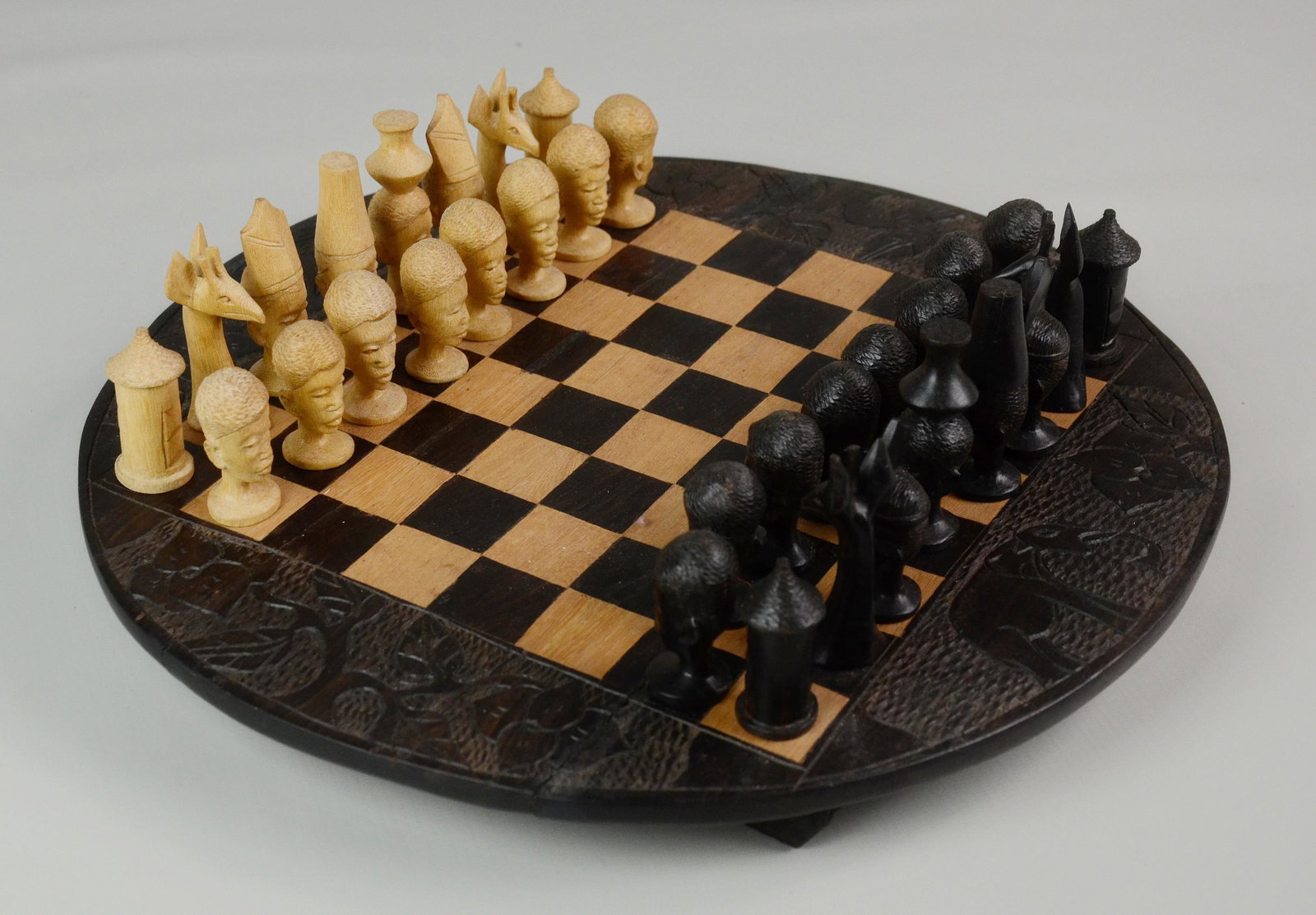 African Carved Wood Chess Set: African carved wood chess set, game board with alternating inlaid squares, animal & floral carvings around edge, 32 carved game pieces, board approx 13" dia