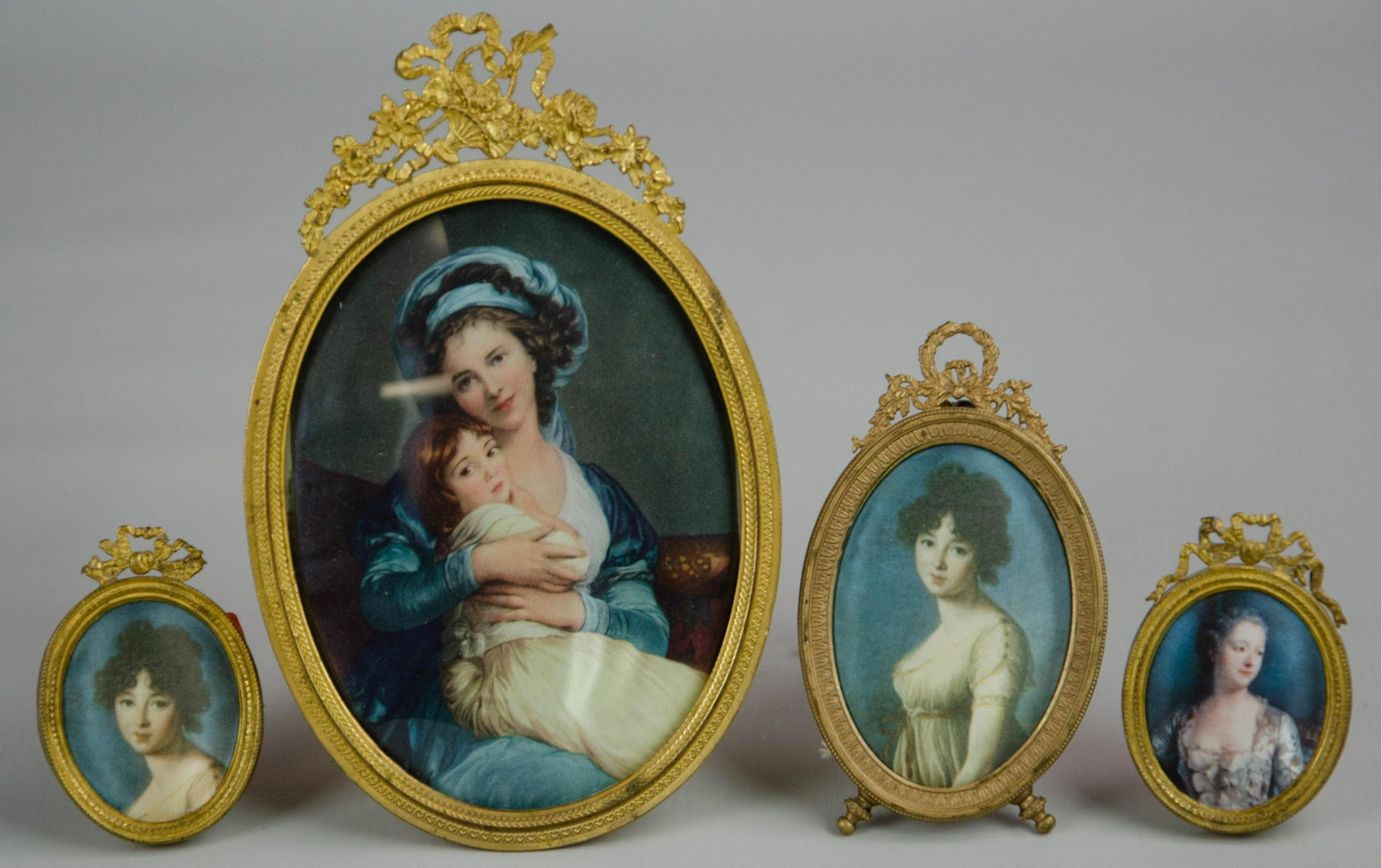 Oval Ormolu and Brass Picture Frames: Oval ormolu and brass picture frames c/o (1) larger gilt brass frame with convex glass and floral ormolu at top, 7-1/2", (1) 4-1/2" oval frame with ormolu wreath at top and decorated feet, and (2) 3" 