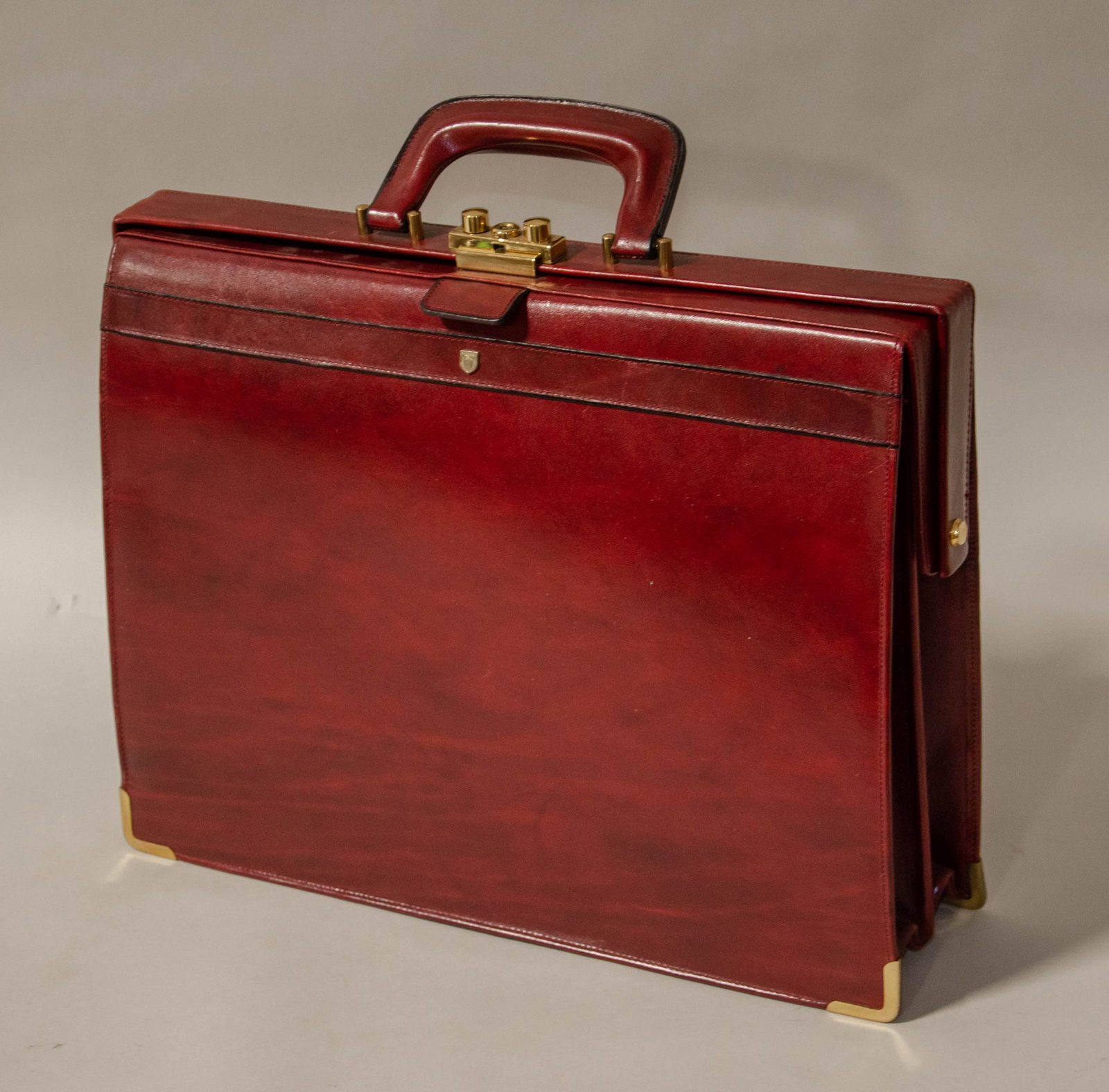 German Leather Attache Case: German leather attache case in cordovan with gold tone hardware, appears unused. Includes key, and (3) compartment interior, 16" W 13" H 4-3/4" D