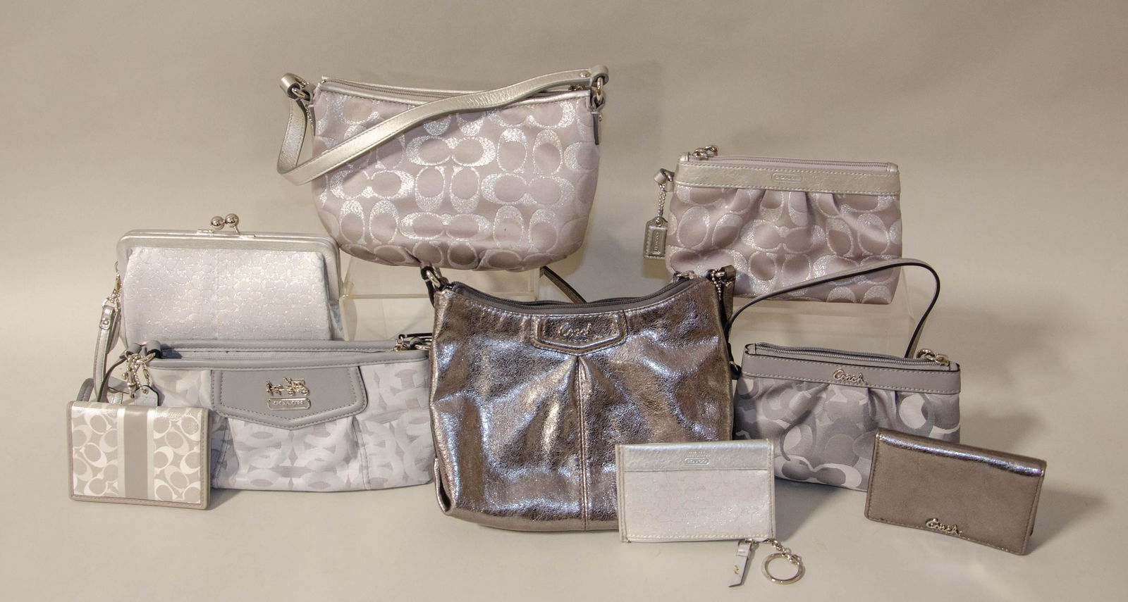(10) Silver Coach Bags and Wallets: (10) Silver Coach bags and wallets c/o (2) silver monogram bifold wallets, monogram wristlet, silver metallic monogram clutch, (2) silver monogram petite wristlets, silver metallic monogram shoulder b