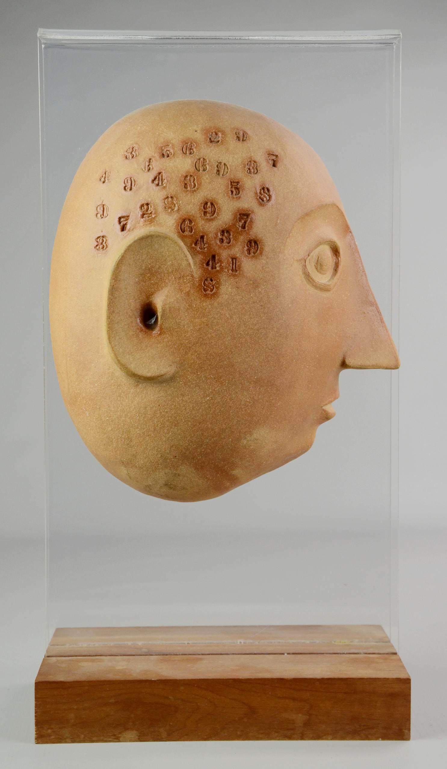 David Gil Bennington Potters Split Head Sculpture: David Gil Bennington Potters split head sculpture c/o pottery head form with impressed numbers on curved lucite frame set in wood stand, signed at interior. Gil, a Vermont artist, was active between 1