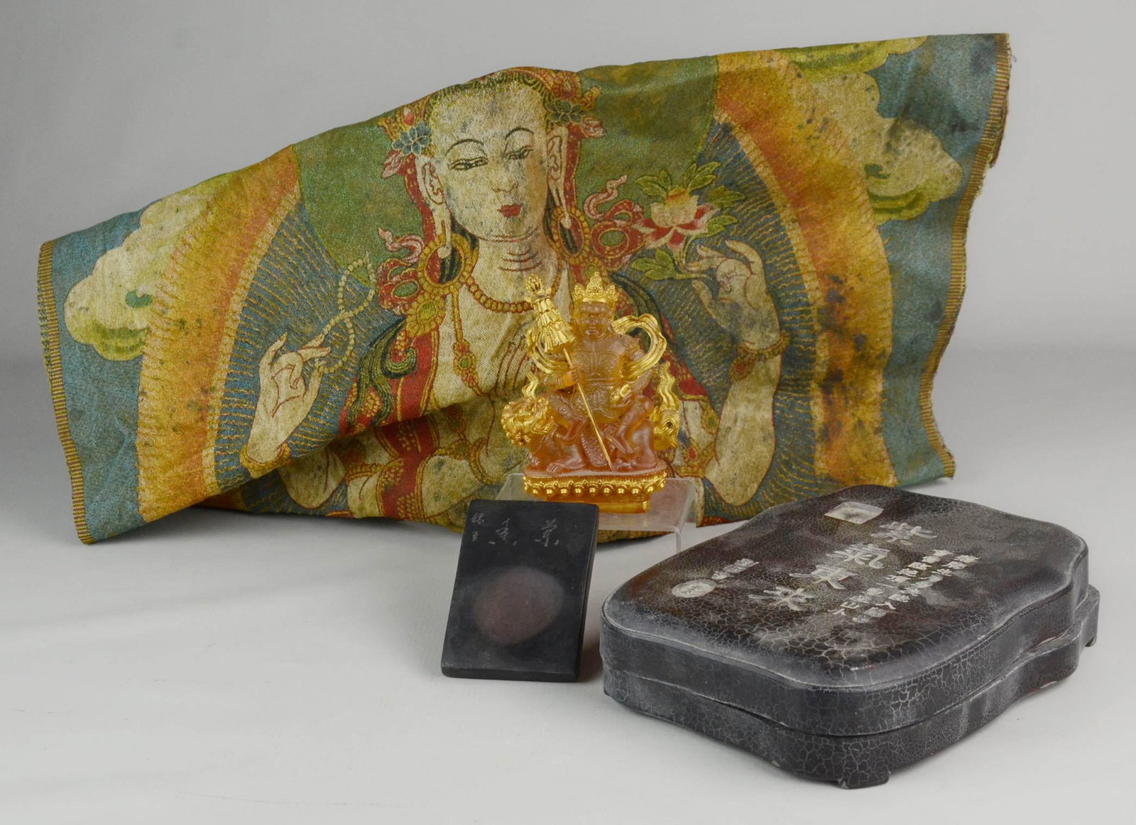 (4) Asian Pieces: (4) Asian pcs c/o Tibetan Thangka, Chinese ink stone w/calligraphy, covered box w/calligraphy, and stylized glass figure w/mythical animal, largest 34" x 23"
