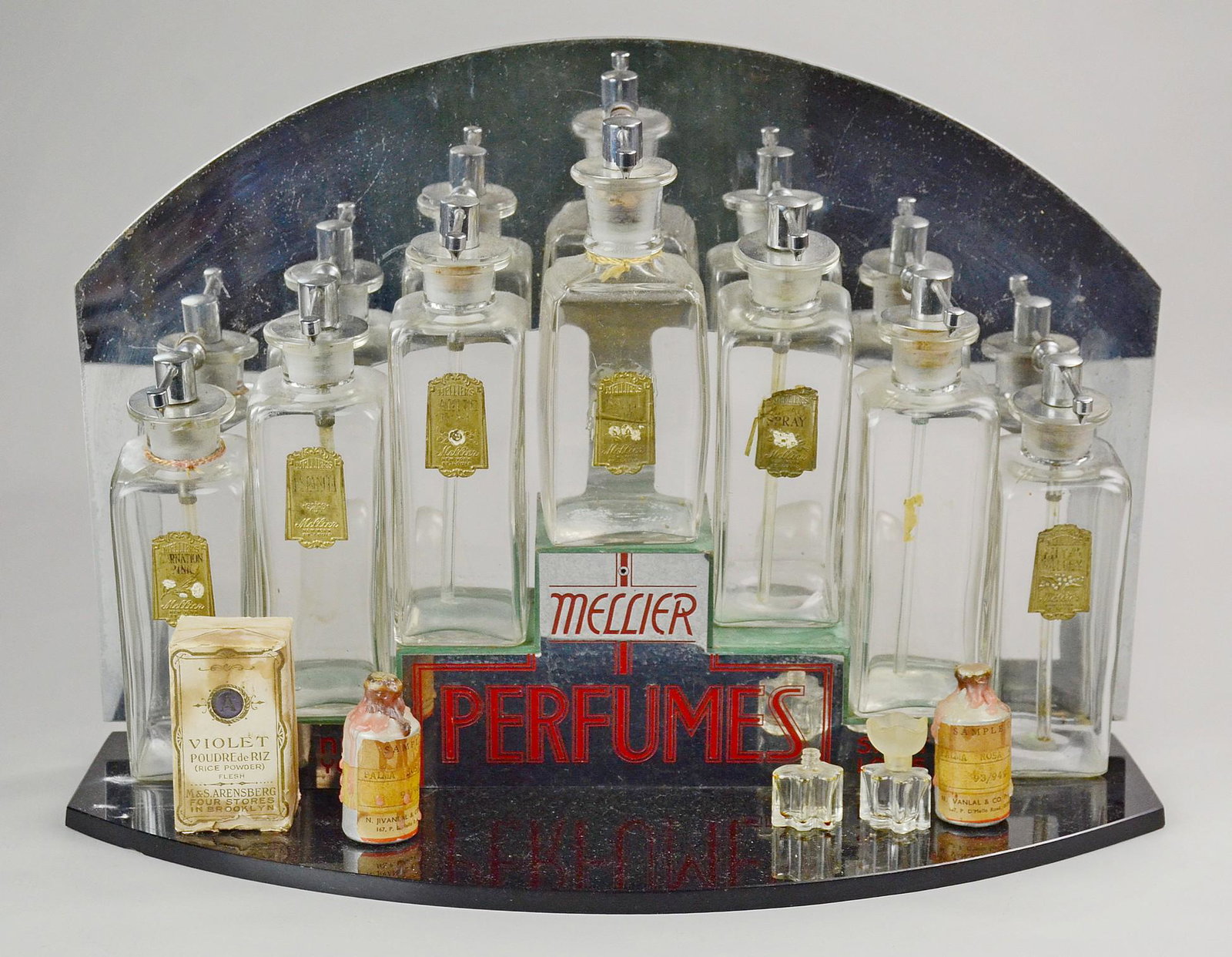 Mellier Art Deco Perfume Display: Mellier Art Deco perfume display c/o black glass and mirrored stand with tiered display supporting (7) Mellier perfume bottles, (6) with original labels reading 'Lilly of The Valley, Lilac, Sweet Pea,