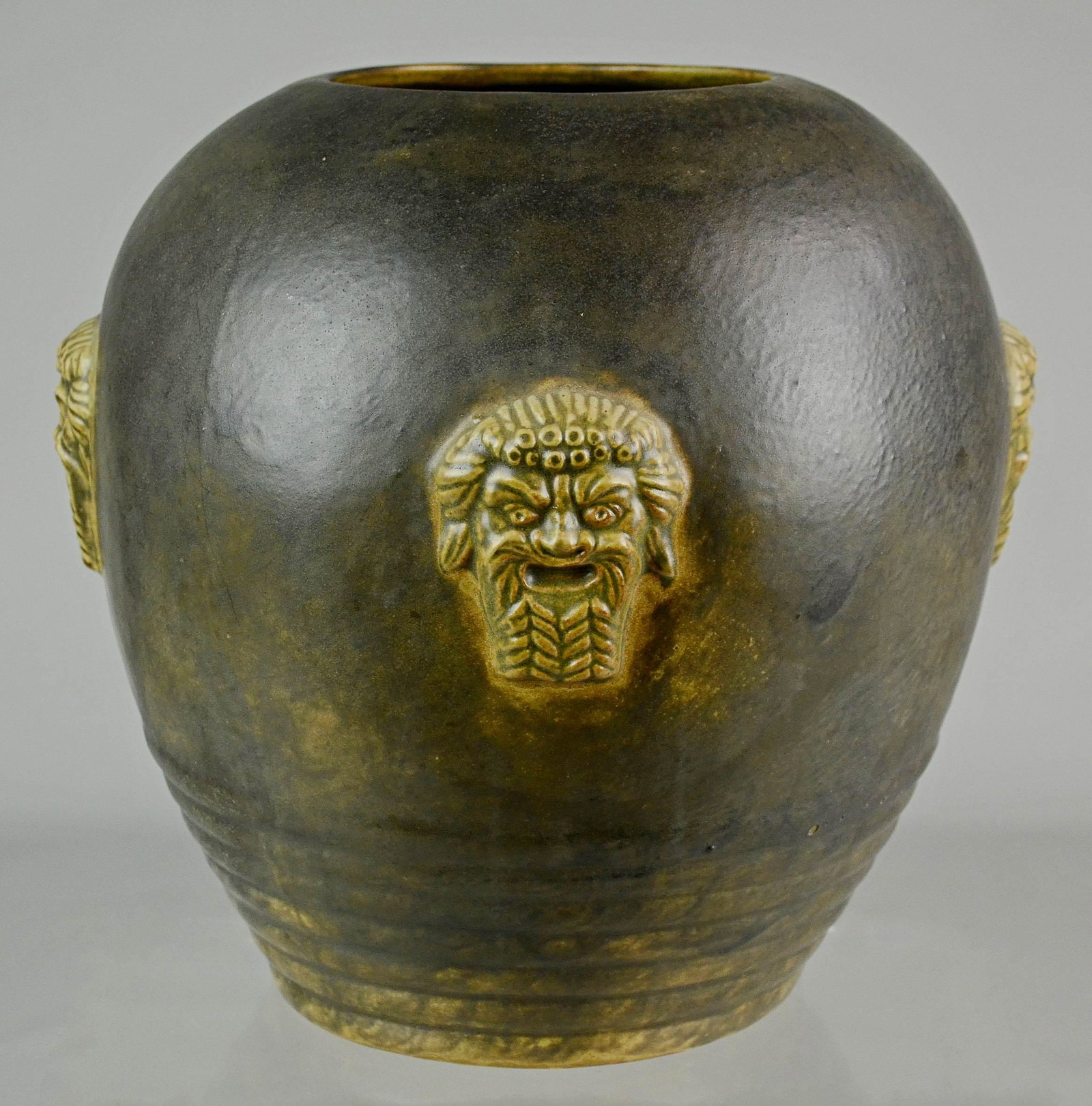 Primavera Art Deco Vase: Primavera Art Deco vase comprised of glazed pottery with 4 Grecian inspired faces surrounding, ribbed bottom, 11" w, 13" h, no flaws to note.