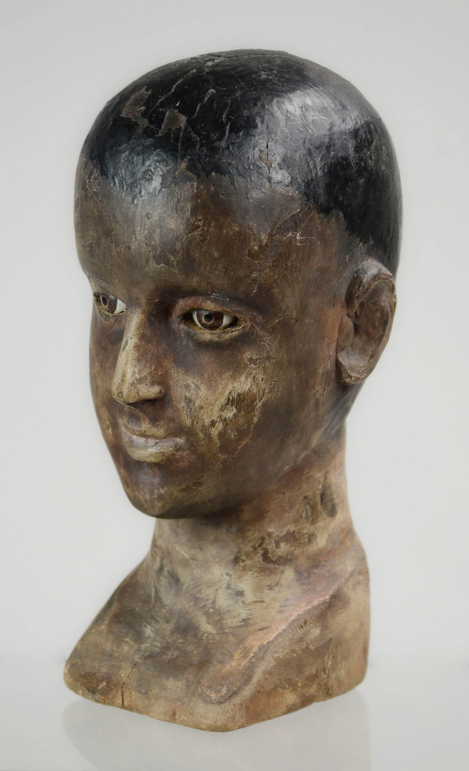 Carved Bust of Young Boy: Carved bust of young boy in painted decoration with glass eyes, 9-1/2"