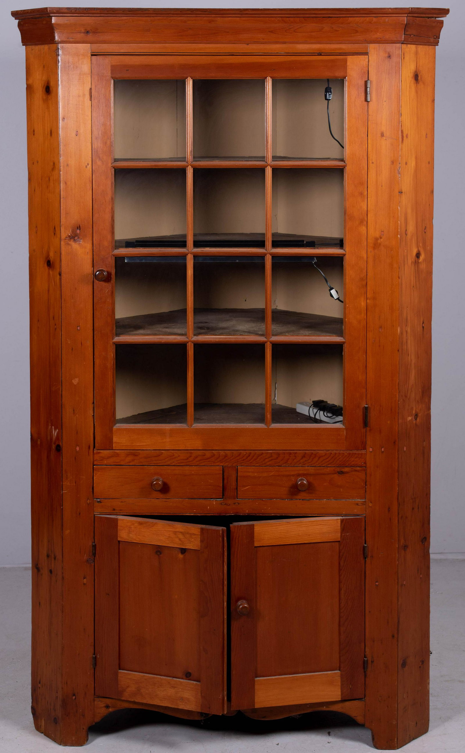 Pine one pc 12 pane corner cabinet: Pine one pc 12 pane corner cabinet, top door with interior shelving, over two replaced drawers over two doors, 78-1/4" h x 44" w x 24" d, new interior lighting