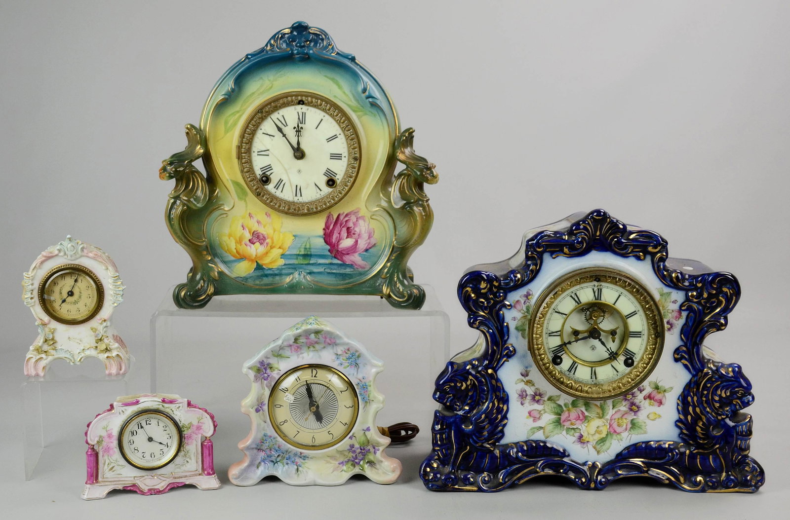 (5) China Case Clocks: (5) China case clocks, c/o Ansonia "Radical" (cracked dial), Royal Bonn with stylized lions (cracked dial), Lanshire Self Starting (electric), 2 unsigned, largest 11" x 13-1/2"