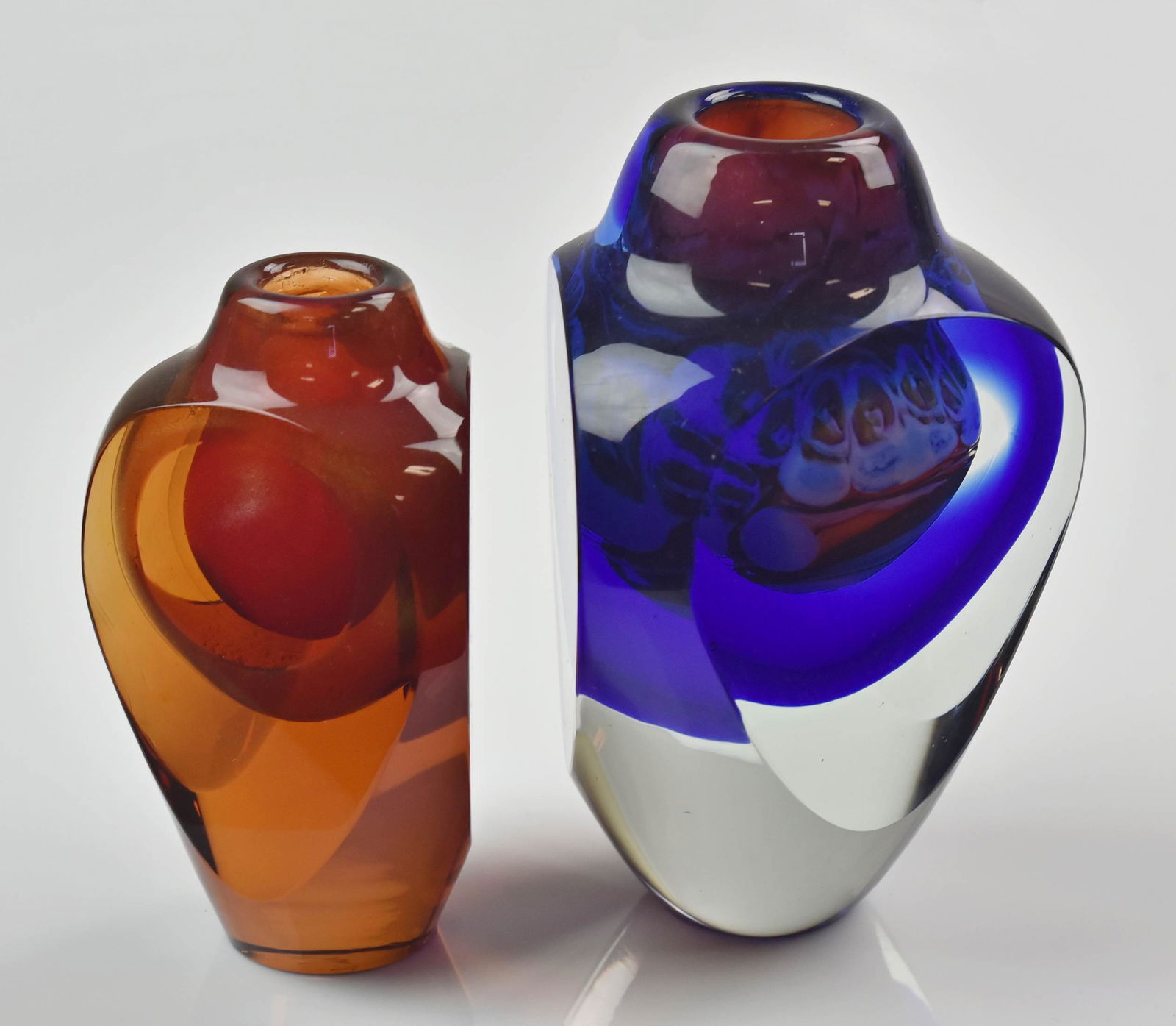 (2) Jon Kuhn Sculptural Vases: (2) Jon Kuhn sculptural vases c/o cobalt, clear and swirled glass 6" vase and clear, amber shimmer and red 5" vase, both signed underside 82' and May 82'