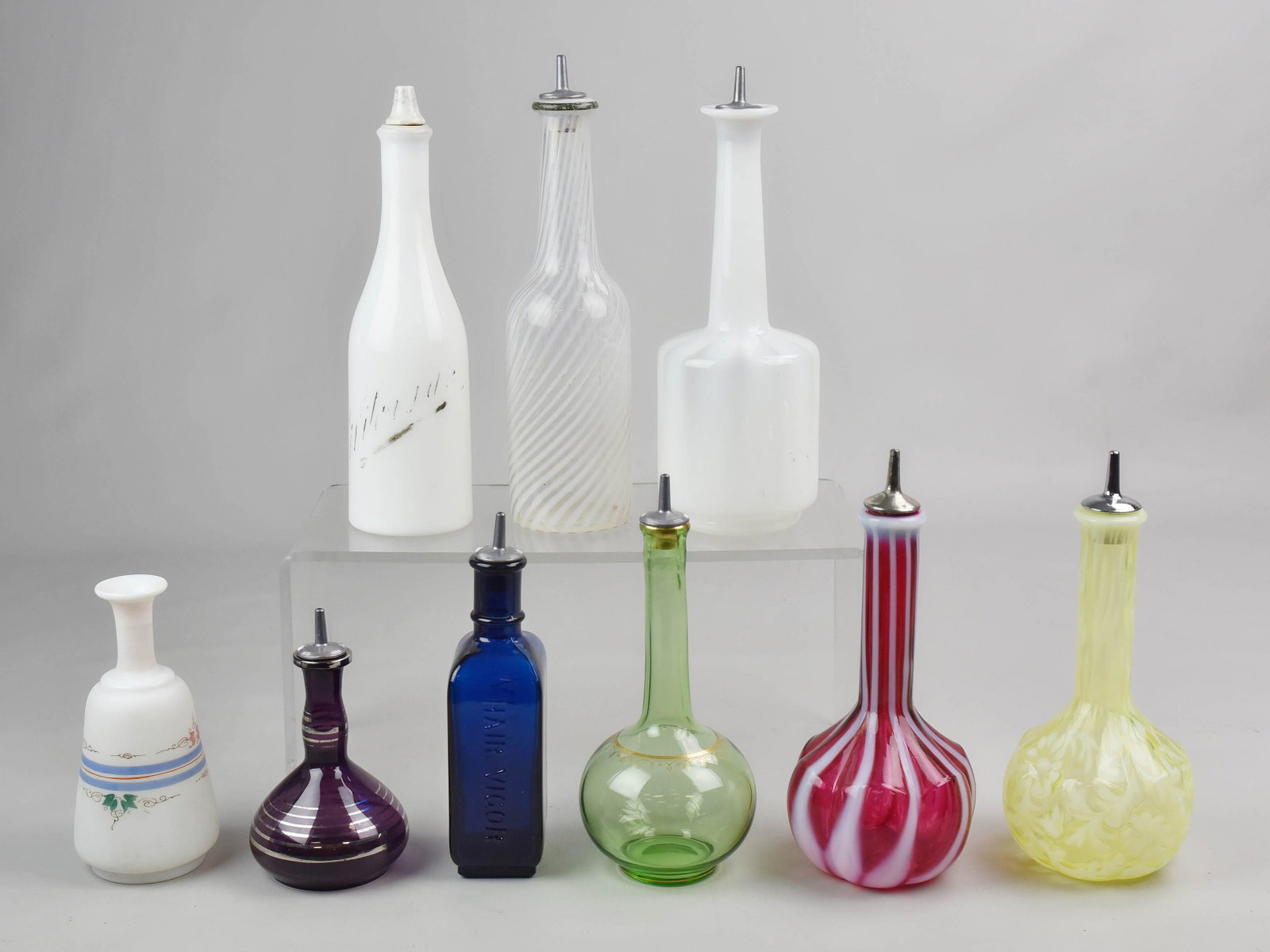 (9) Glass Barber Bottles: (9) Victorian barber bottles c/o yellow daisy, 7-1/2", opalescent striped cranberry, 7-1/2", opalescent opaque stripe on opalescent sheer, 9", spiral opalescent 9", amethyst glass with silver highligh