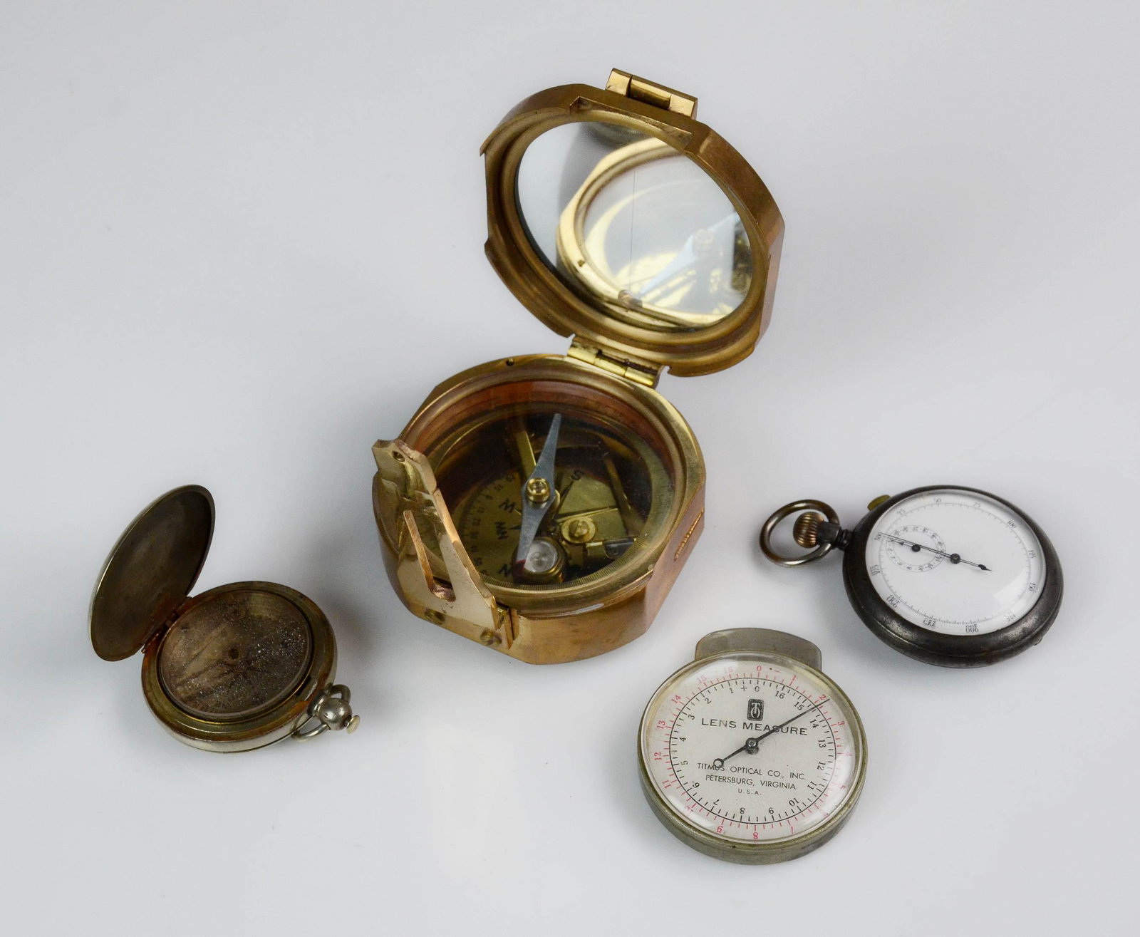(4) Measuring Instruments: (4) Measuring instruments, c/o Natural Sine India brass nautical compass with sine conversion chart & mirrored lid, Keuffel & Esser Surveyors Railroad Pocket Compass, Titmus Optical Co Lens Measure, S
