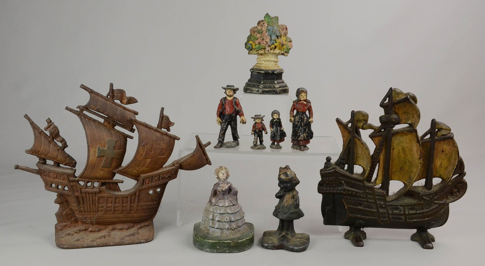 (9) Cast Iron Door Stops/Figures: Cast iron grouping c/o (2) cast iron ship form door stops, bouquet form door stop, figural female doorstop, child form door stop, and (4) cast iron Amish figures c/o man, woman and (2) children.