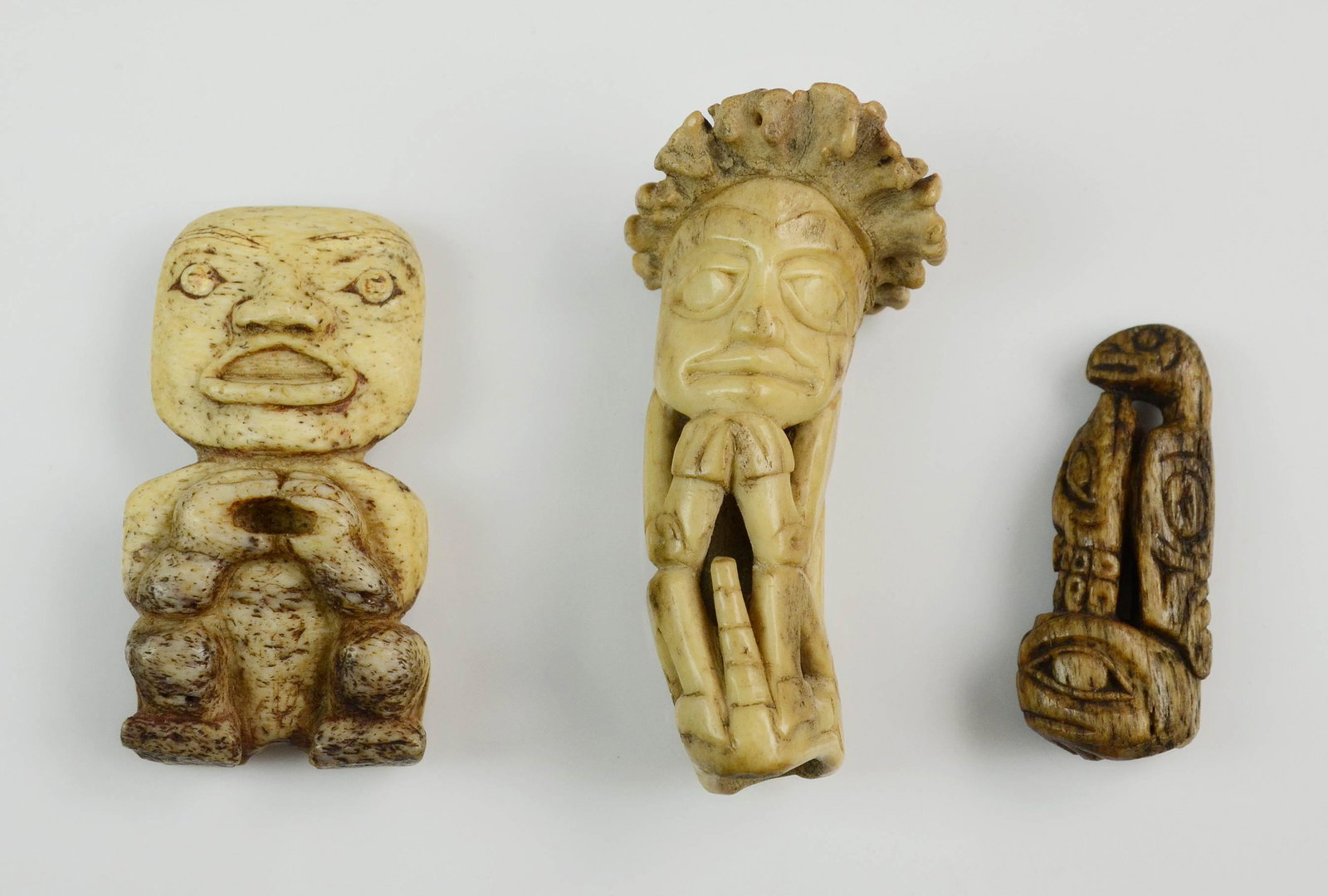 3) Carved Bone/Antler Northwest Coast Tlingit amulets: (3) Northwest Coast Tlingit amulets: carved bone woman with labret, 3" h, in a fitted box with estate label dating it pre-1880; carved antler seated figure with animal face verso, 3 3/8" h; carved bon