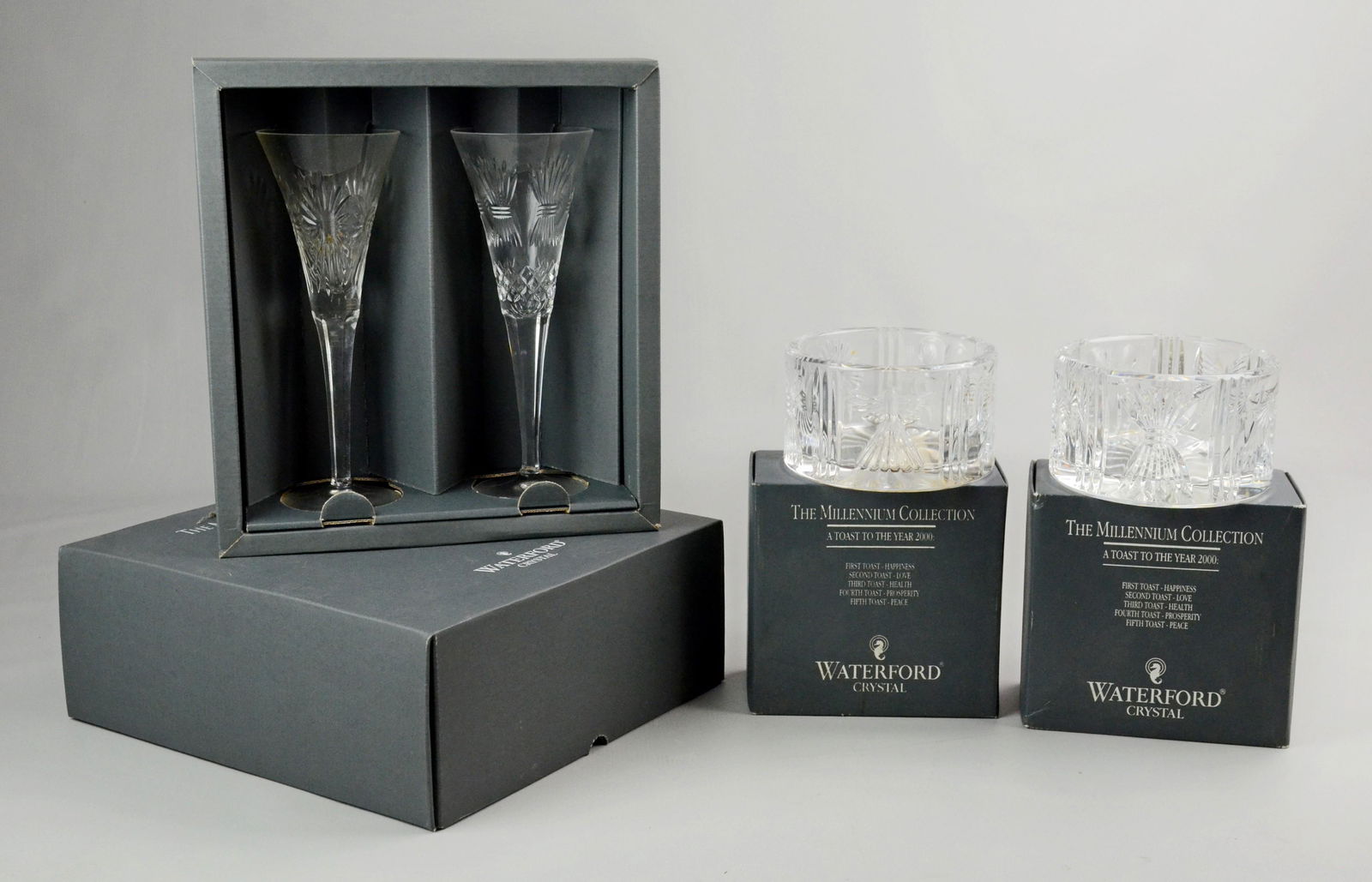(12) Pcs Waterford Millennium Collection: (12) Pcs Waterford crystal Millennium Collection, c/o (10) toasting flutes (9" h), 2 each Happiness, Love, Health, Prosperity, Peace, and (2) wine bottle coasters (5-1/4" dia x 3" h), all in original