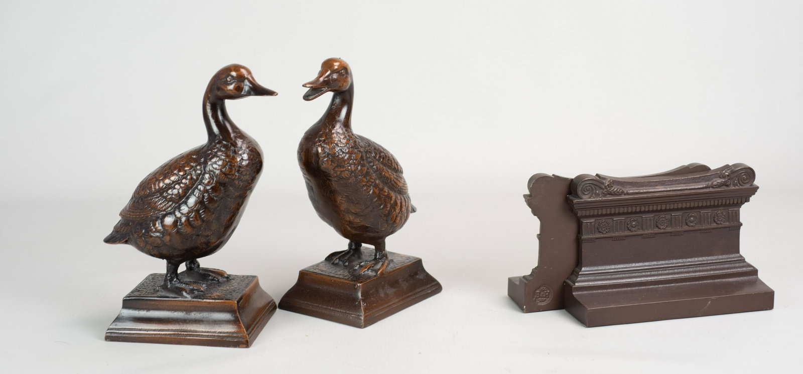 (2) Pr Figural Bookends: (2) Pr figural bookends c/o Bradley Hubbard column form bookends in bronze, 7"x4-3/4" h, signed lower back and bronze patinated duck form bookends, 9" h