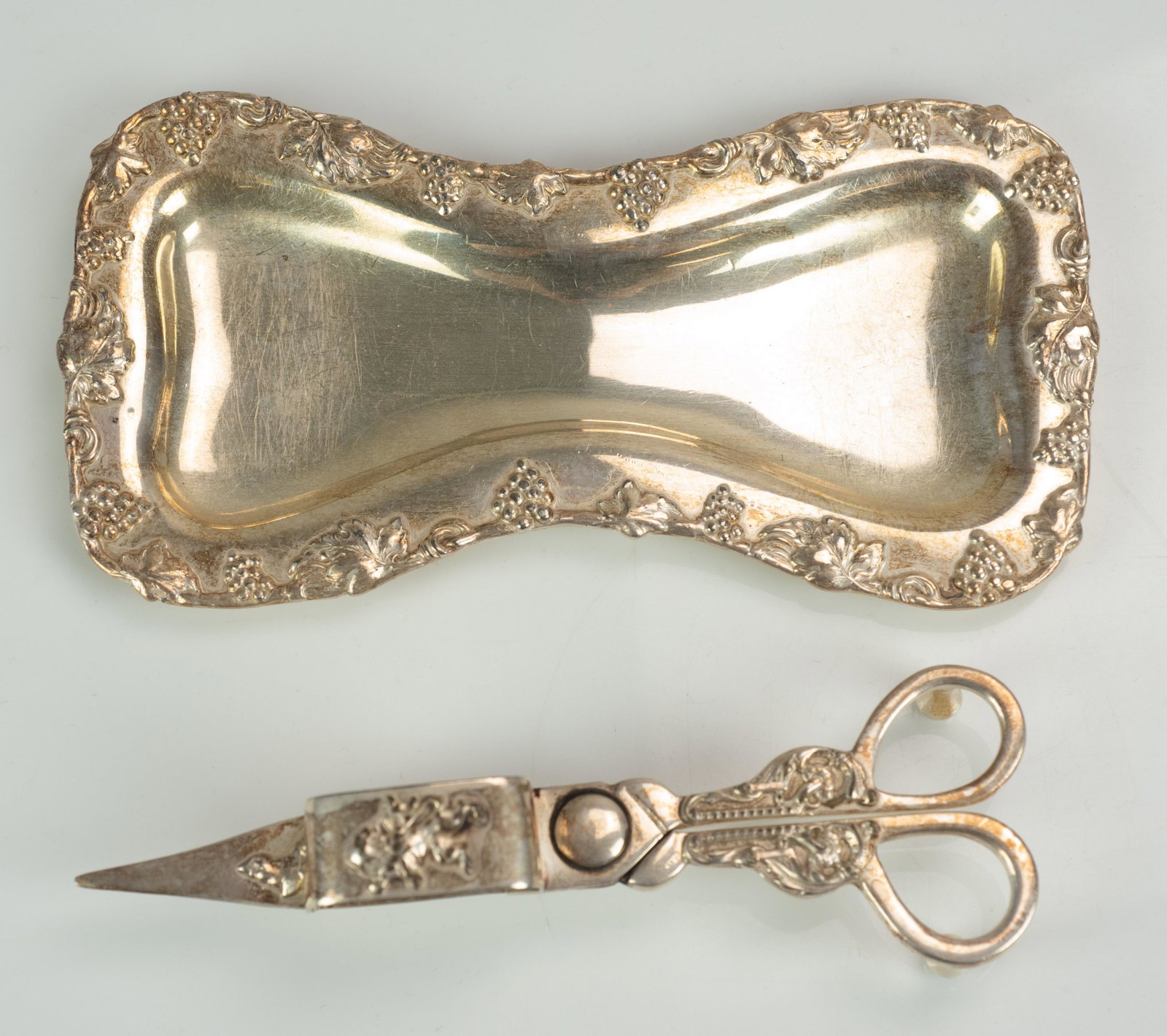 Lawrence B. Smith Silver Snuff Scissors and Underplate: Lawrence B. Smith silver snuff scissors and underplate in repousse vine and grape decoration with lion statant at snips top, 8" undertray, 7" snips, 11.4 T.O