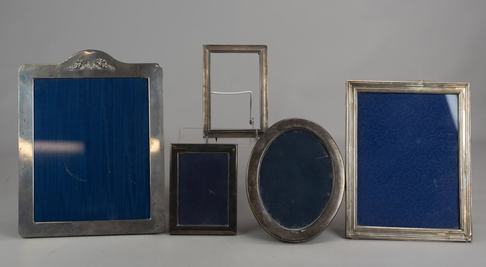 (5) Sterling Mounted Frames: (5) Sterling mounted picture frames including angel crested, (3) rectangular in varied size and oval form, 6-1/4" through 13", some with denting, (1) missing backing and glass and (1) engraved 'Harris