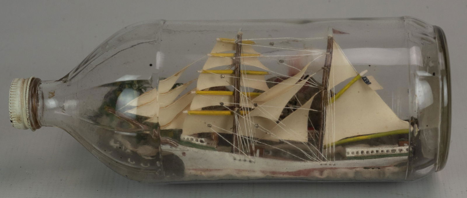 Ship in Bottle Miniature: Ship in bottle, constructed inside early 20th c. Heinz Ketchup bottle, double mast ship with hillside houses and volcano in back, 9-1/4"