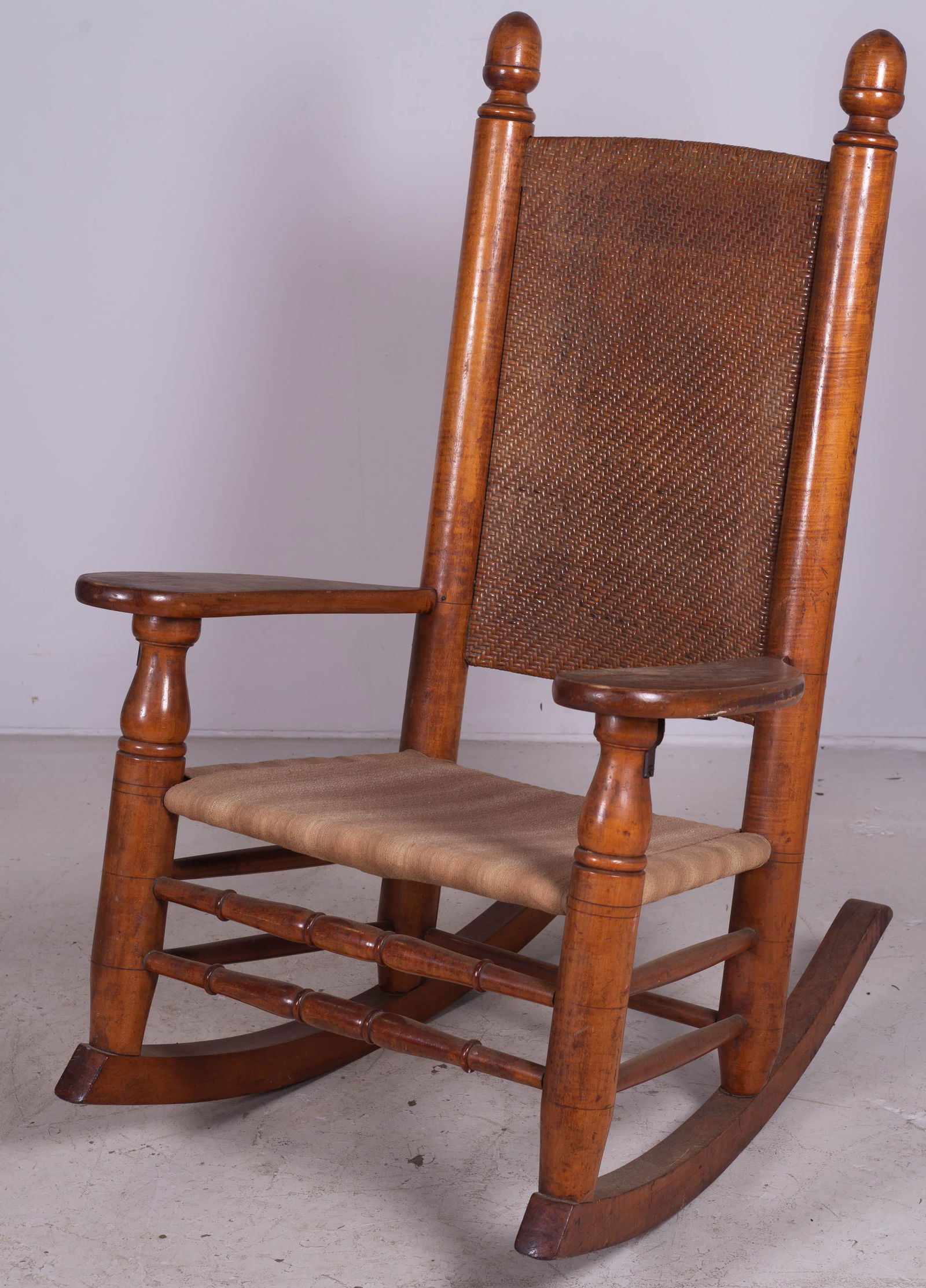 Maple woven back rocking chair: Maple woven back rocking chair, caned back upholstered seat, acorn finials, 47" h, seat height 17" h
