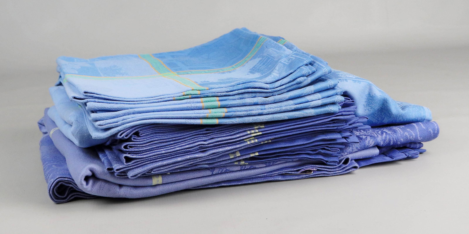 (2) Le Jacquard Francais Tablecloths and Napkins: (2) Le Jacquard Francais tablecloths and napkins c/o (1) periwinkle and cream coated jacquard tablecloth 88" x 66" with (12) dinner napkins and (1) light blue, mint and cantaloupe 68" x 66" tablecloth