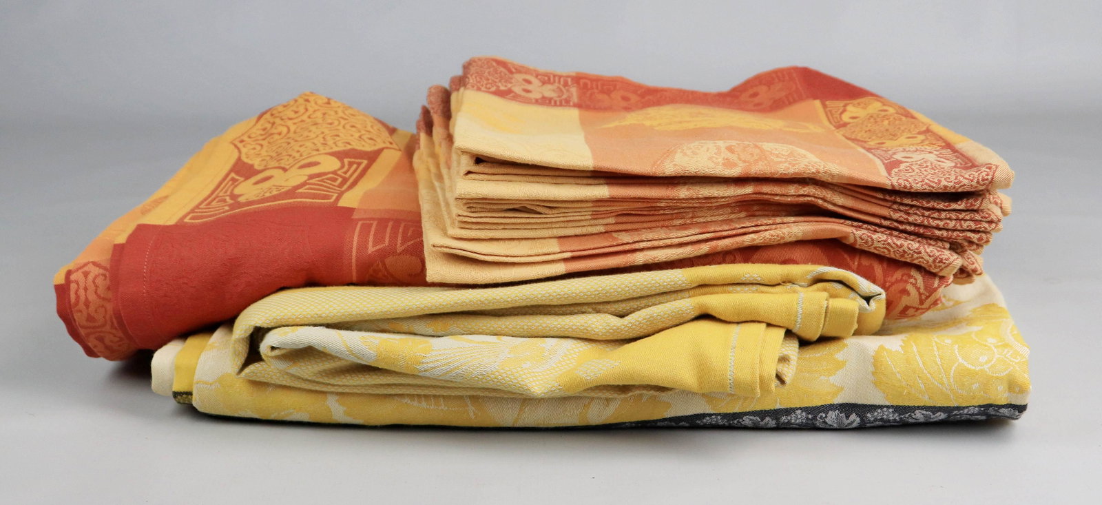 (3) Le Jacquard Francais Tablecloths and Napkins: (3) Le Jacquard Francais tablecloths and napkins c/o (2) unmatched yellow and cream jacquard tablecloths, 92" x 68" and 94" x 68", (1) with spots and (1) monochromatic orange toned tablecloth, 98"x68"