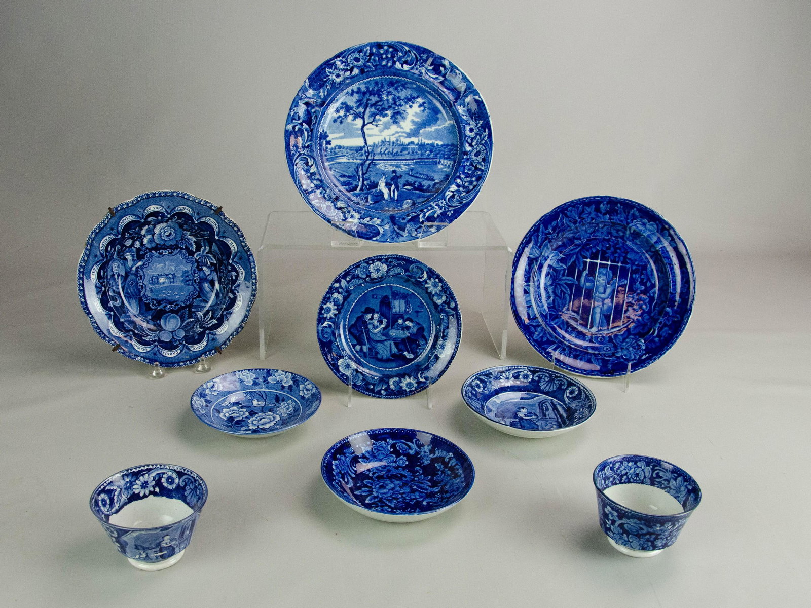 (9) Pcs Blue Transfer Staffordshire: (9) Pcs Blue transfer Staffordshire, c/o Clews "America & Independence" 8-3/4" dia shallow bowl (crack), "Christmas Eve" plate 6-3/4", Cherub behind bars 9"plate, "Fair Mount Park Near Philadelphia" 1