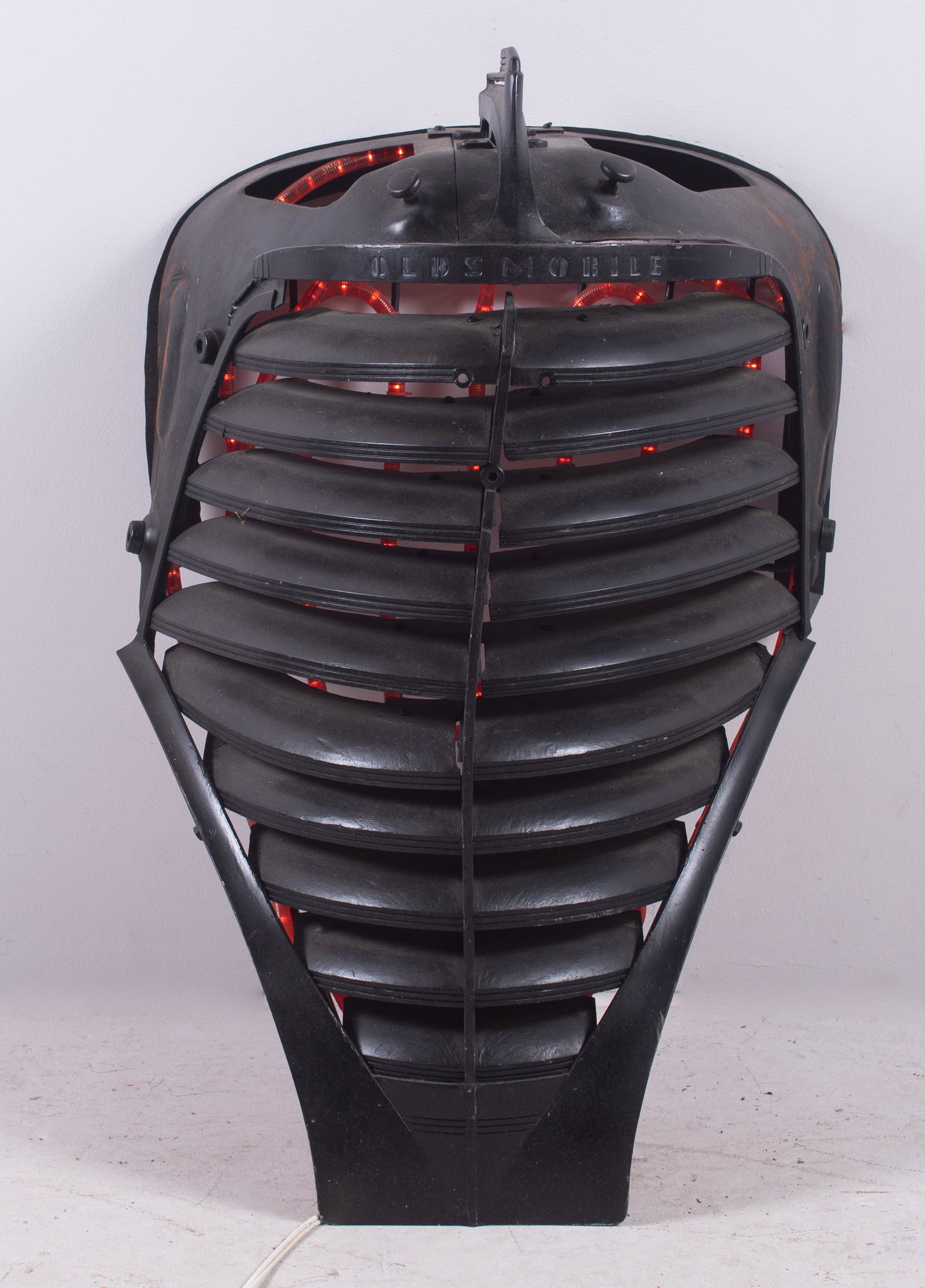 Janet Sullivan Turner Auto Sculpture "Oldsmobile": Janet Sullivan Turner (American, b 1935) PA artist, automobile sculpture "Oldsmobile", black painted Oldsmobile grill with installed red rope lighting, signed "Janet Sullivan Turner 2002", 32" x 22" x