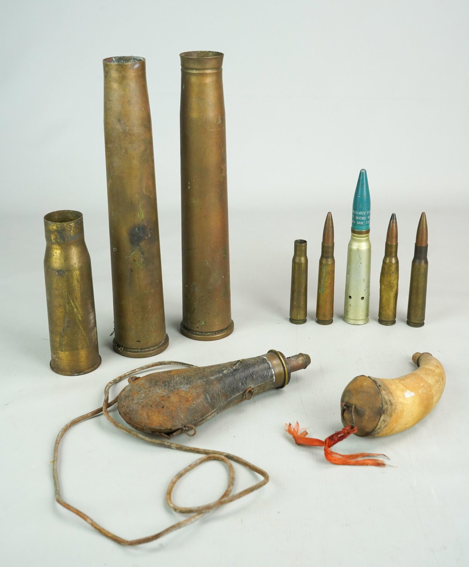 Powder Horns, Ammunition and Artillery Shells: Powder horns, Ammunition and artillery shells c/o 19th c. carved horn powder horn reading 'F.M.J 1883' with gun images, leather cased powder horn, unmarked, (2) 12" 40's artillery shell, 6-1/2" artill