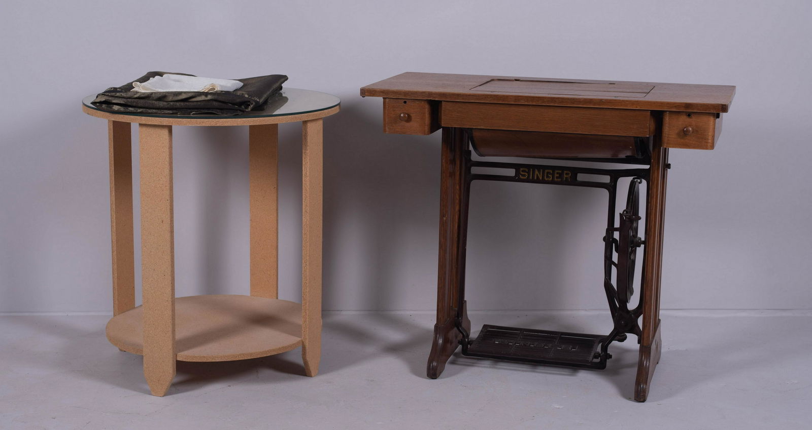 Singer oak treadle sewing machine, round table: Singer oak treadle sewing machine two drawers, 29" h x 33-1/2" w, along with plywood table covered with table drape and glass top