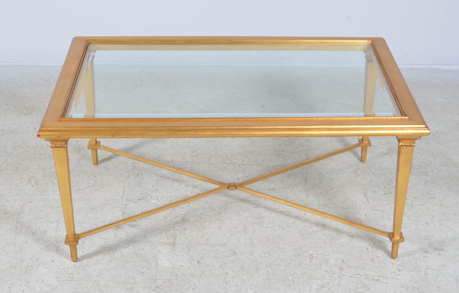 Gold Painted Coffee Table: Gold painted rectangular coffee table, cross stretcher base, beveled glass top, 42" L x 26" d x 19" h, Good condition; minor spots of loss on the stretcher. Striations/craquelure on top edges.