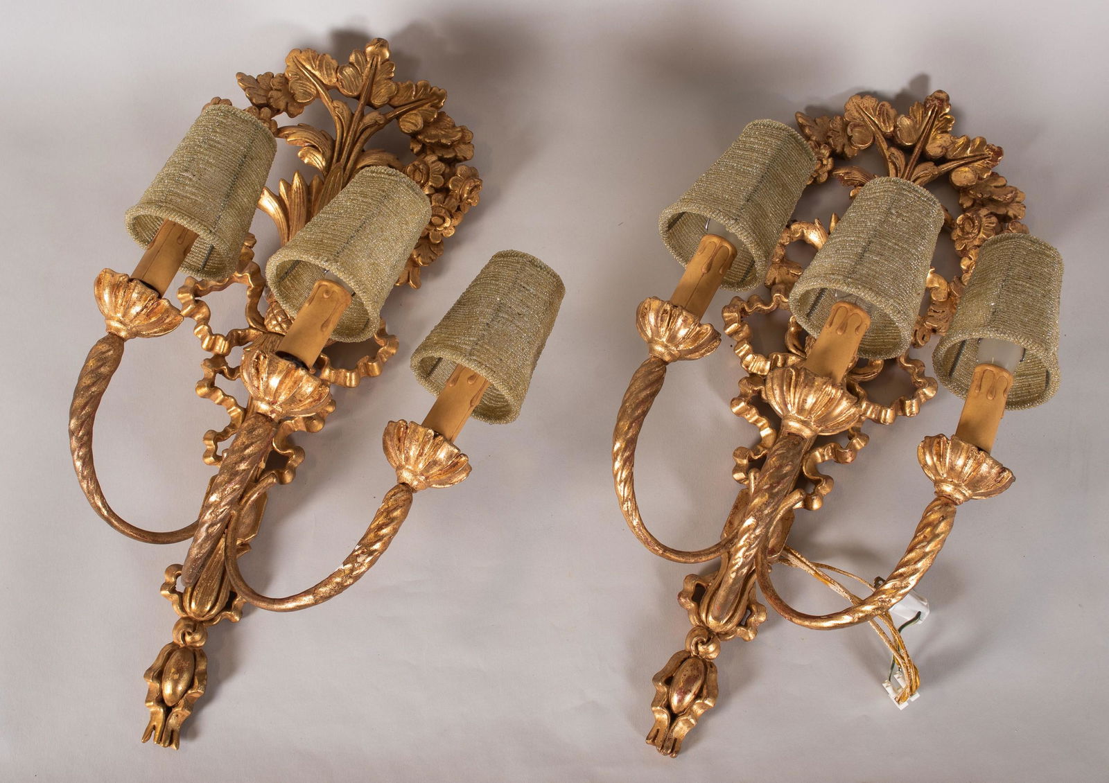 Pair Italian Gilt Composite Sconces: Pair Italian gilt composite sconces in 3-light construction with faux candle form casing and flower, twist and bow carved details, 22" h, (1) with chips to gilt at arm.