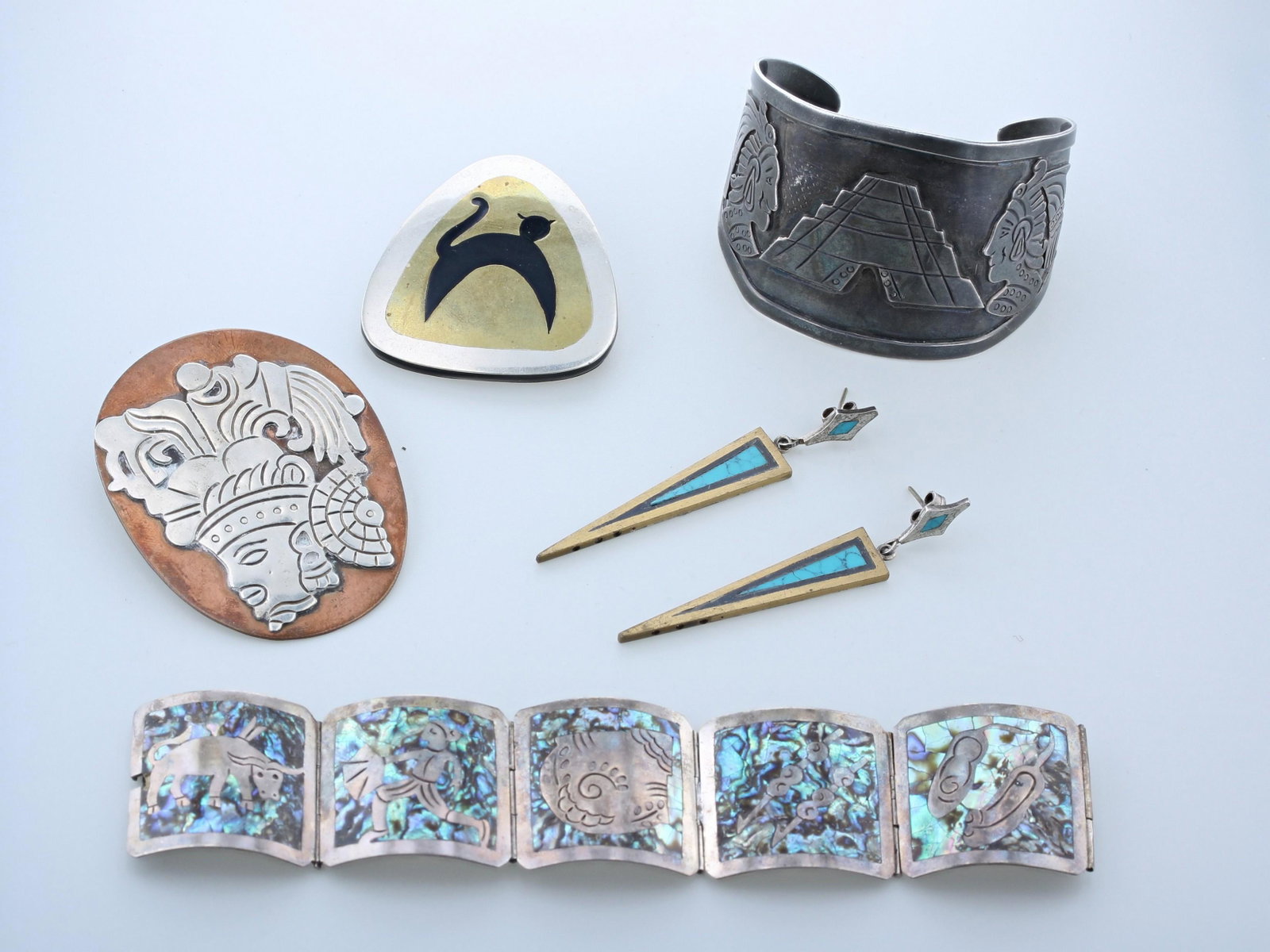 Mid-Century South American Jewelry: Mid-Century Modernist central and south american Jewelry 5 pc Lot C/O; (1) Bronze, silver and black wood triangle brooch with cat image, (1) copper and silver warrior brooch 2.5" in diameter, (1) Ster