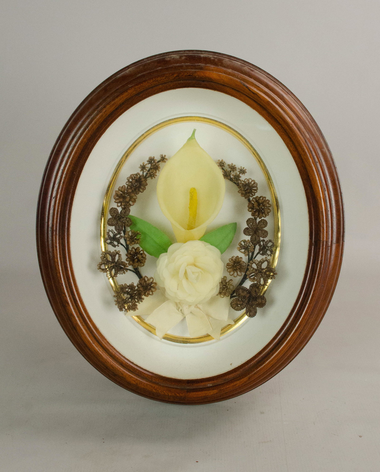 Mourning Hair Art: Mourning hair art with wax flowers tied with ribbon, partial inscription on back "75", in oval shadow box frame, 15" x 13"