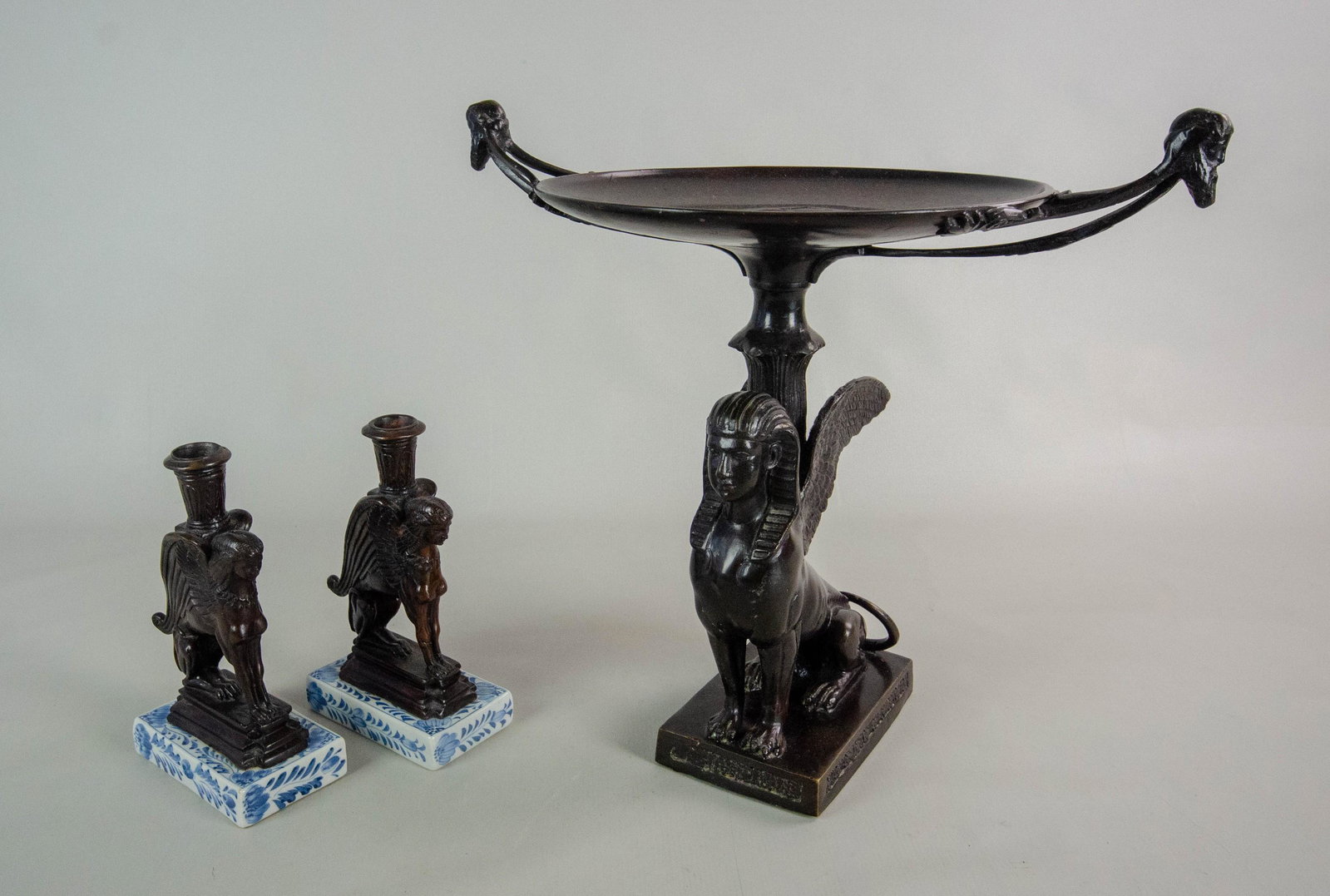 Maitland Smith Bronze Sphinx Console Set: Maitland Smith bronze console set, c/o compote, sphinx base, embossed warrior in bowl, man with beard head handles, 16-1/4" x 10-5/8" x 15-3/8" h, pair of candlesticks with blue & white porcelain base