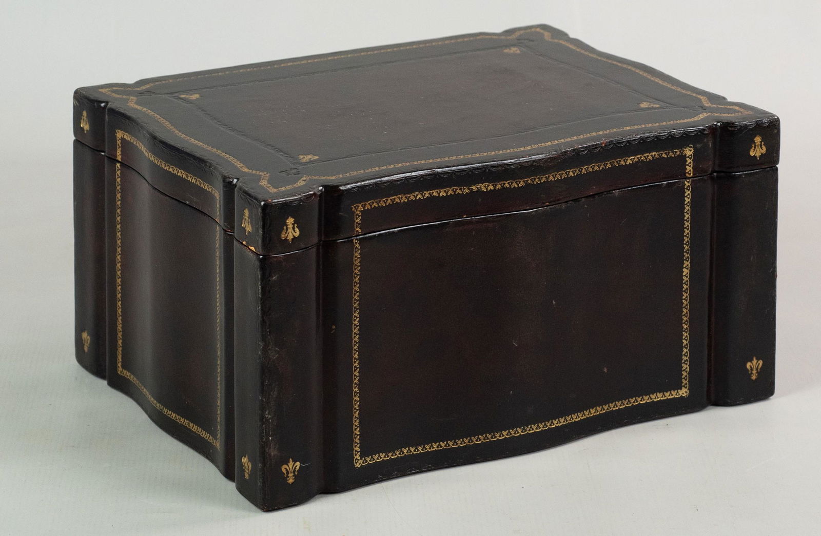 Maitland-Smith Leather Clad Box: Maitland-Smith leather clad box with gilt embossed trim and fleur de lis decorated corners, ebonized interior, 12"x9"x6-1/4"