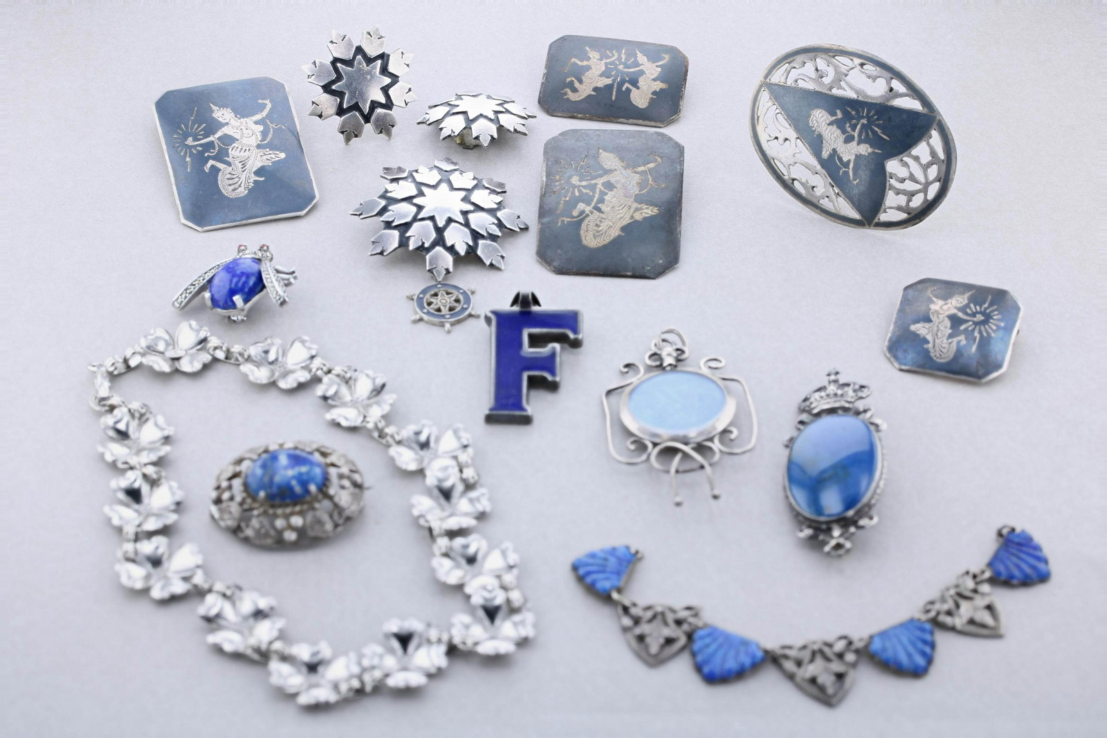 Sterling Silver and Silver Jewelry: Sterling Silver and silver jewelry lot c/o: (1) Signed Peruzzi Brooch in Sterling, (1) Art deco silver plated necklace part, (5) Siam Brooches, (1) Lee Bernard Inc. marcasite brooch, (1) Danecraft Ste
