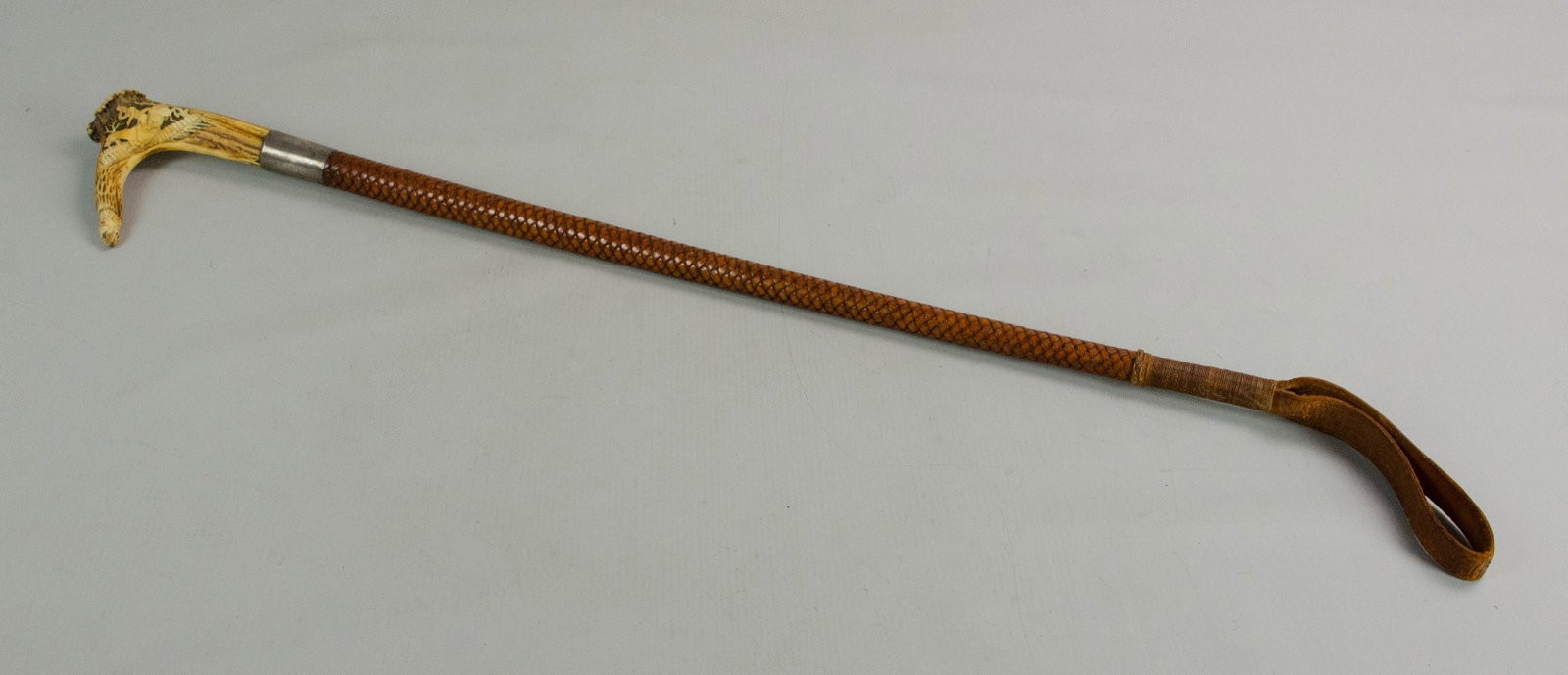 Carved Antler Riding Crop: Carved antler riding crop, man on horseback jumping fence on one side, man falling off horse on the other side, silver mounting with German memorial engraving dated 1949, 29-1/2" l