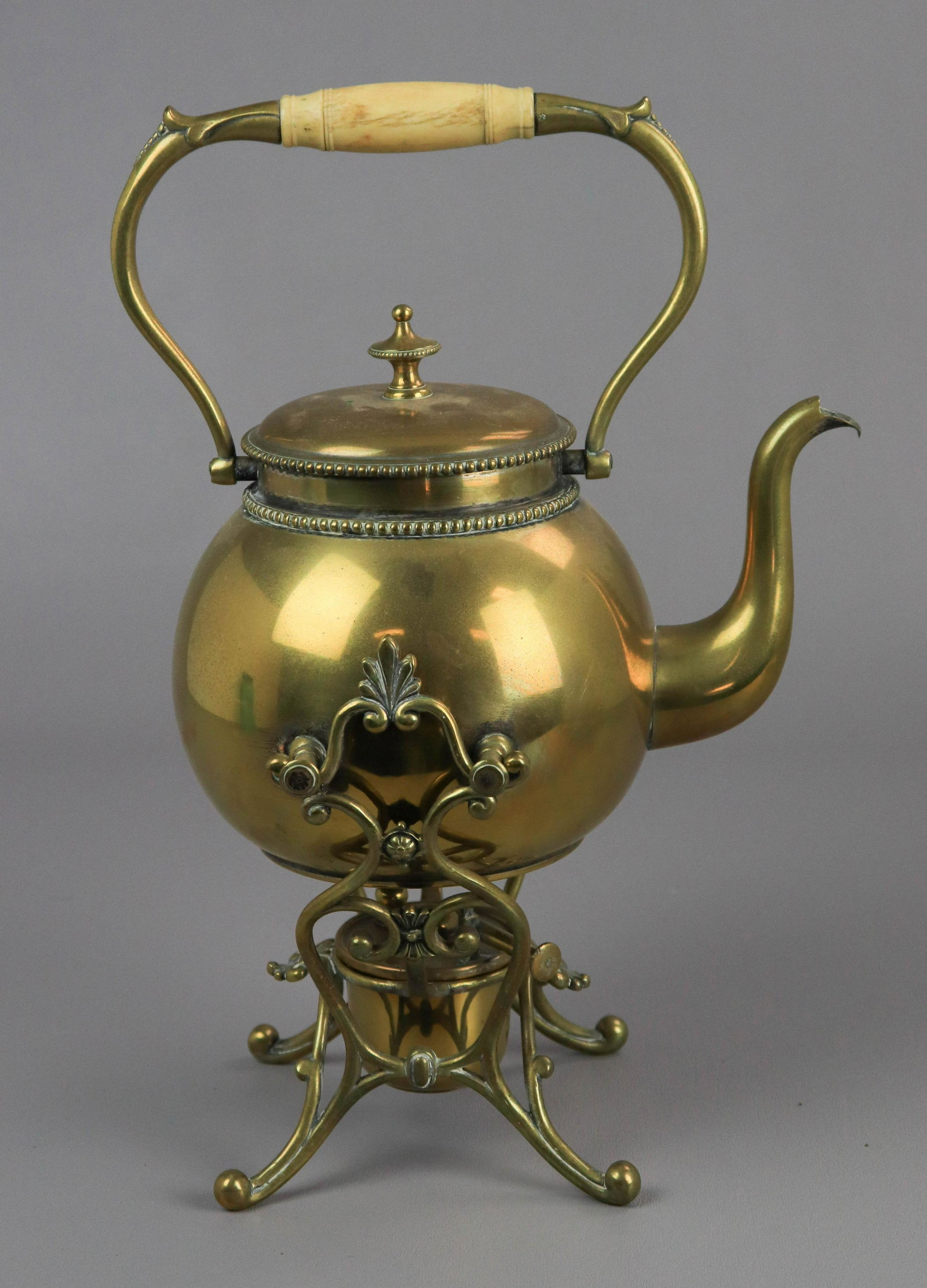 Brass Tilting Tea Kettle with Warmer: Brass tilting teapot kettle on stand with warmer, bone handle, 11" h, Tea kettle had one broken arm where it rests on stand;