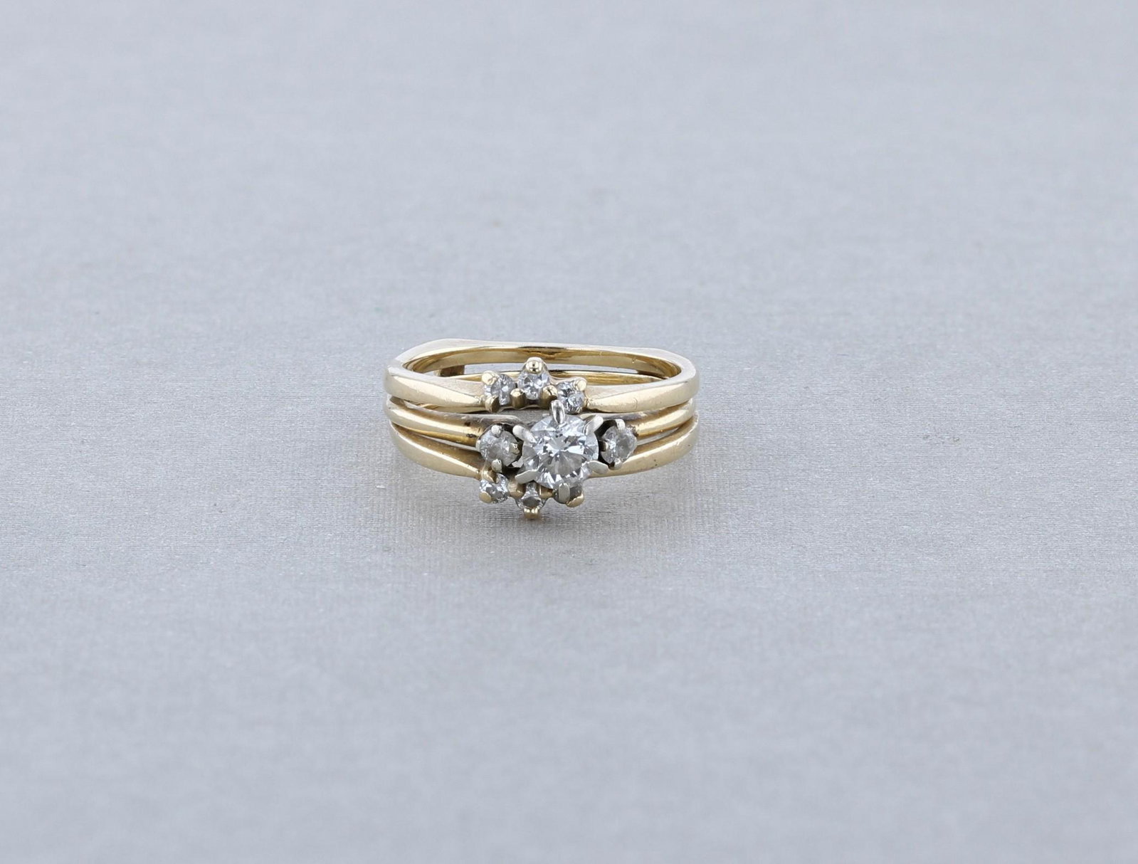 Yellow Gold Diamond Wedding Set: (1) 2pc wedding set marked 14K. The main ring is composed of one 4.5mm diamond flanked by two 2.3mm diamond, the ring enhancer is made with six 1.8mm diamonds. Size approx. size 5.5, ring enhancer / r