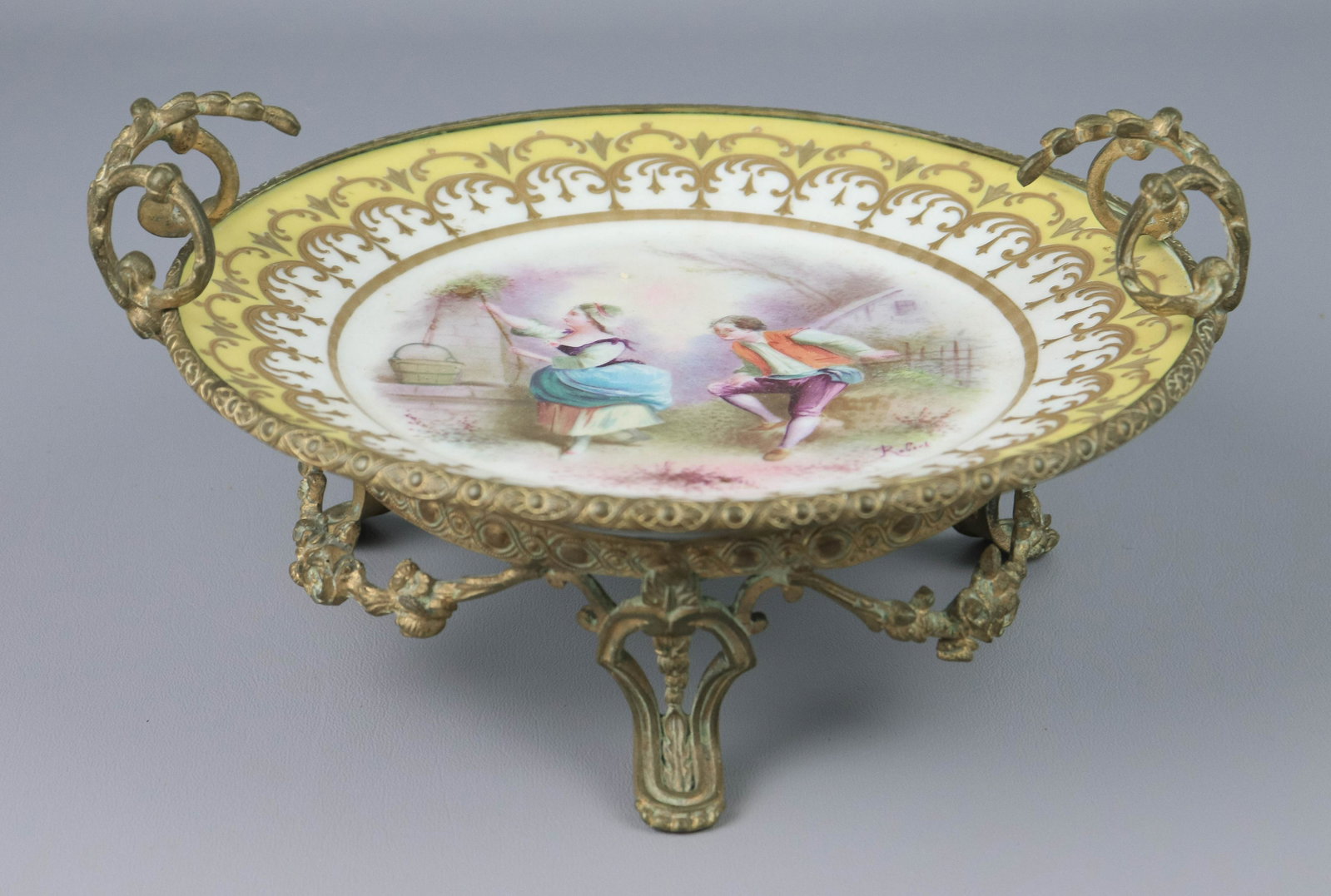 Vincennes-Sevres Hand Painted Plate in Stand: Vincennes-Sevres hand painted plate in stand c/o parcel gilt plate with hand painted courtin scene at center, signed Robert, mounted in footed gilt metal stand, 11" x 5-1/2" , plate marked S-41 France