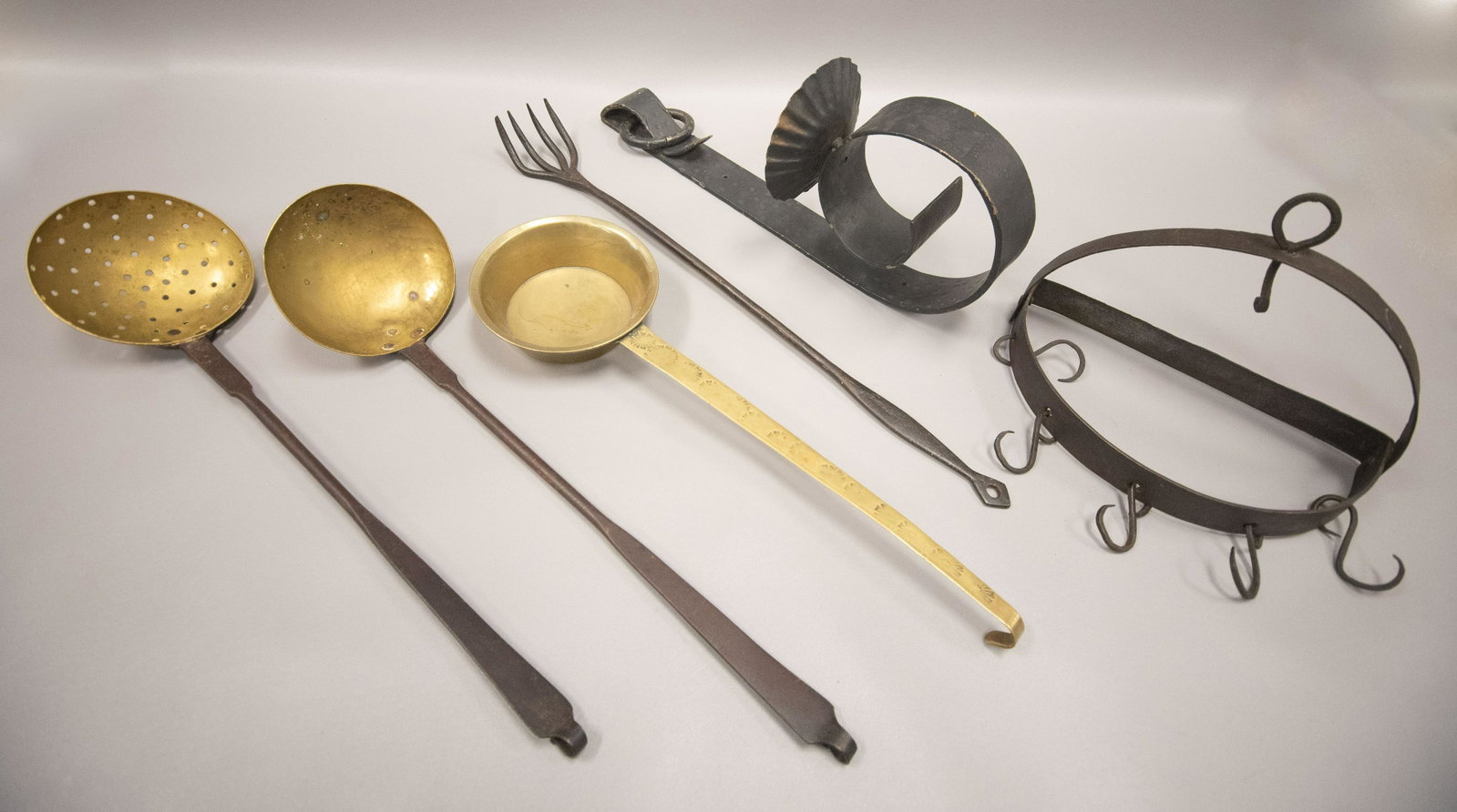 Cast Iron Implement Rack and Implements: Cast Iron implement rack and implements to include demilune hooked cast iron implement rack, brass cupped ladle, punched brass spoon, iron fork and stamped brass scoop. Also to include iron wall hangi