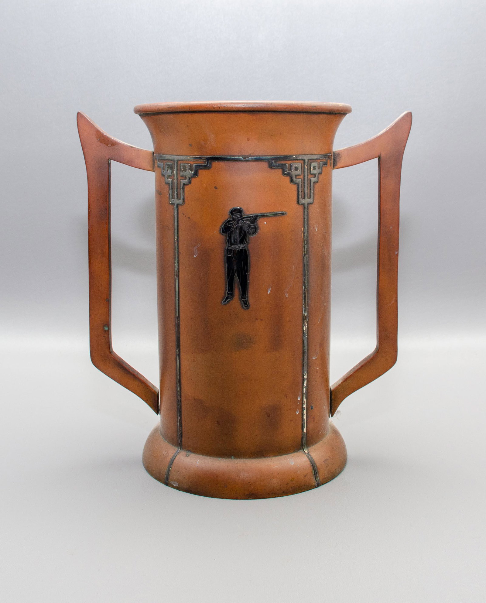 Heintz Sterling on Bronze Art Deco Trophy Cup: Heintz sterling on bronze art deco trophy cup, double handle sides with sterling deco design sterling inlay with sterling figural rifleman badge at front, 10-1/4" hx9-1/2" diam