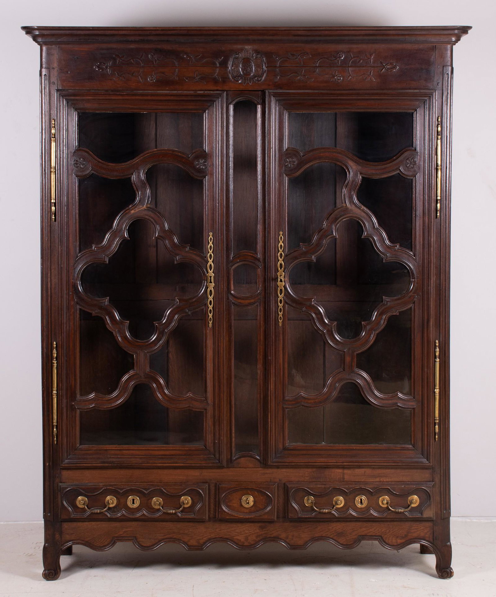 Carved oak French Armoire: Carved oak French Armoire, doors with complex scalloped panels replaced with glass panes, three drawers in base, adjustable interior shelves, 18th c, 65"w x 85"h x 15"d