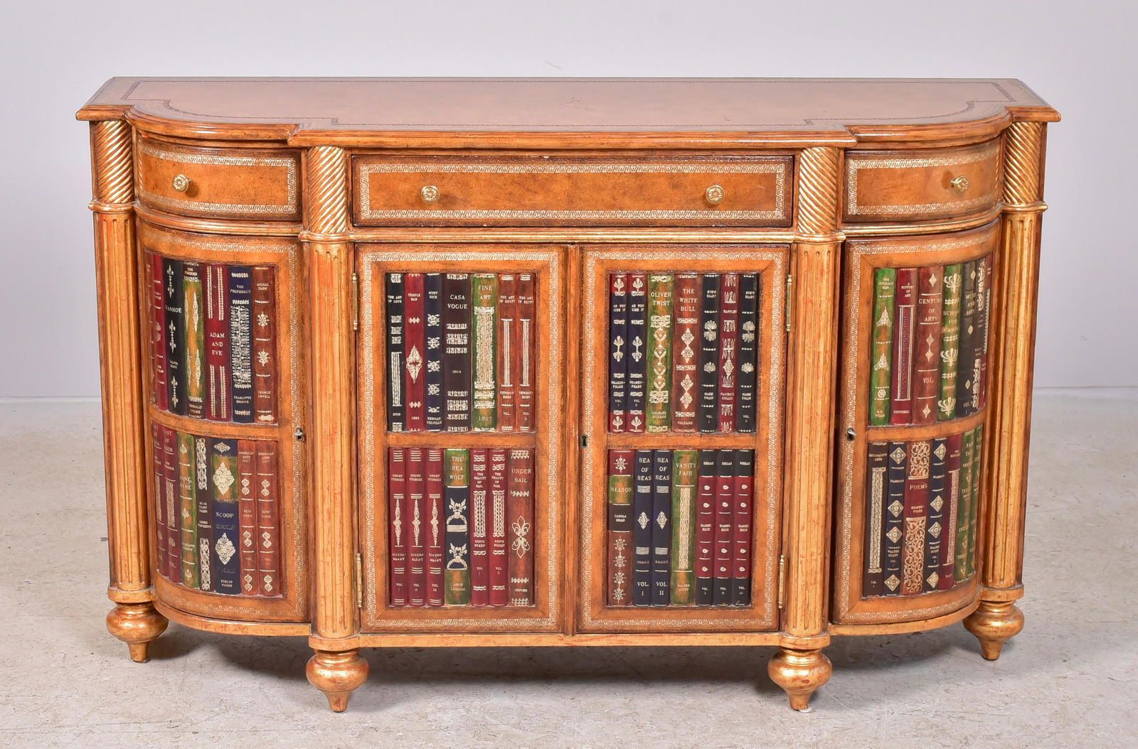 Maitland-Smith Regency Style Credenza: Maitland-Smith regency style credenza with tooled leather top over conforming body with three leather front drawers, over doors with faux book spine decoration.