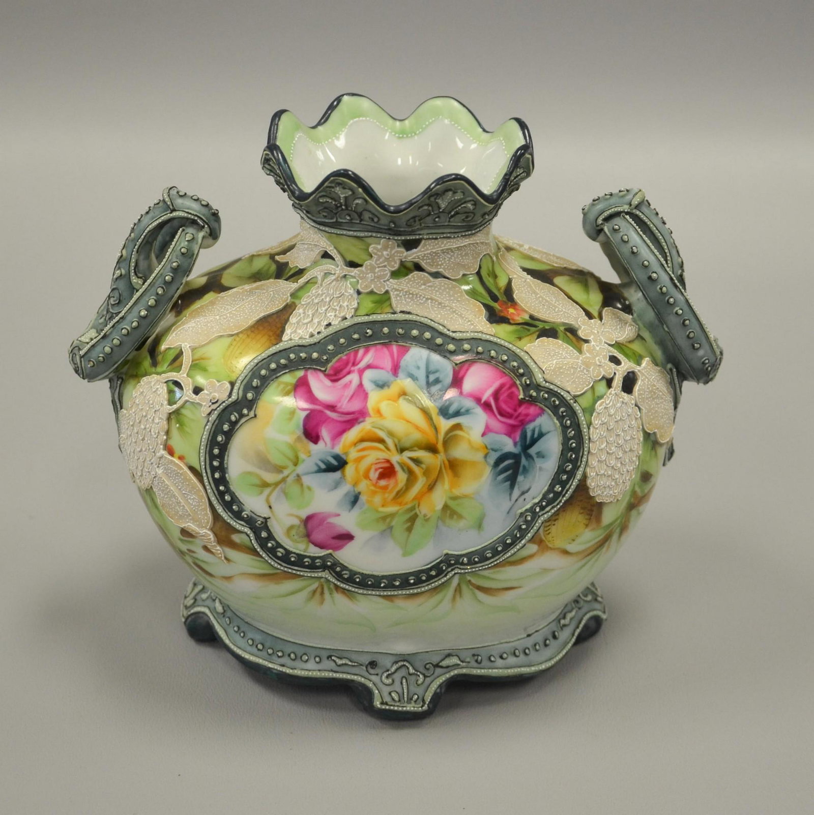 Japanese Nippon Porcelain Moriage Vase: Japanese Nippon porcelain vase, elaborate moriage decoration, interlocking fixed ring handles, hand painted floral decoration, 6-1/4" h x 7-1/2" w