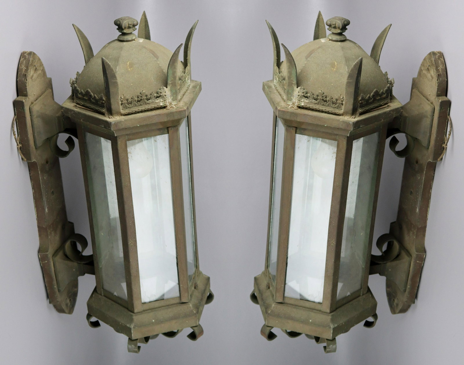 Pair Bronze Architectural Wall Sconces: Pair bronze architectural wall sconces c/o scroll and finial topped elongated hexagonal form with paneled glass sides, cast decorative base with outturned spiked corners, domed base and stylistic bott