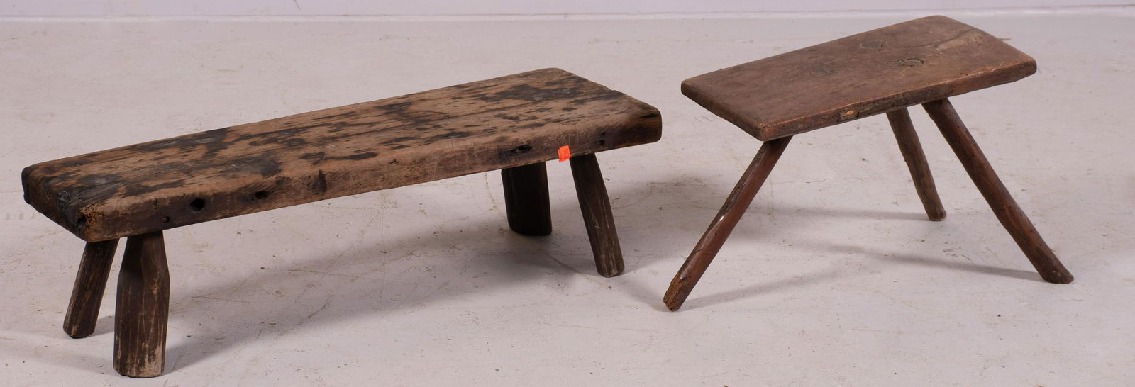 (2) Primitive pine benches: (2) Primitive pine benches, largest 10" h x 32" w, wear to paint, insect damage, small bench with Split in top does not go through. Worm holes, one leg with damage legs have been reglued.