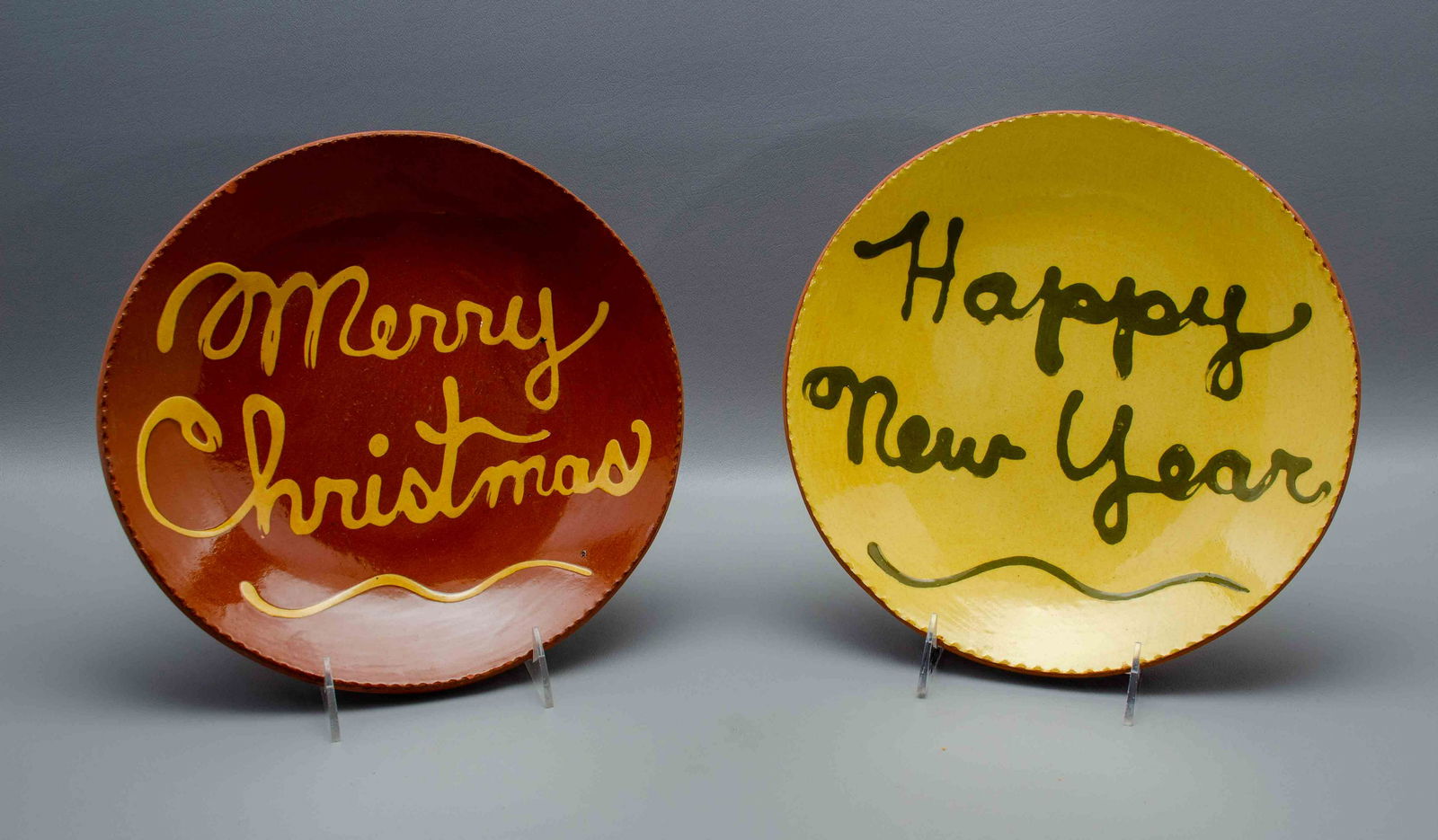 (2) Redware Pottery Plates: (2) Redware pottery plates to include Breininger pottery plate reading 'Happy New Year', signed at back and marked 'cool' and Robesonia plate reading, 'Merry Christmas', small chip at edge, signed at