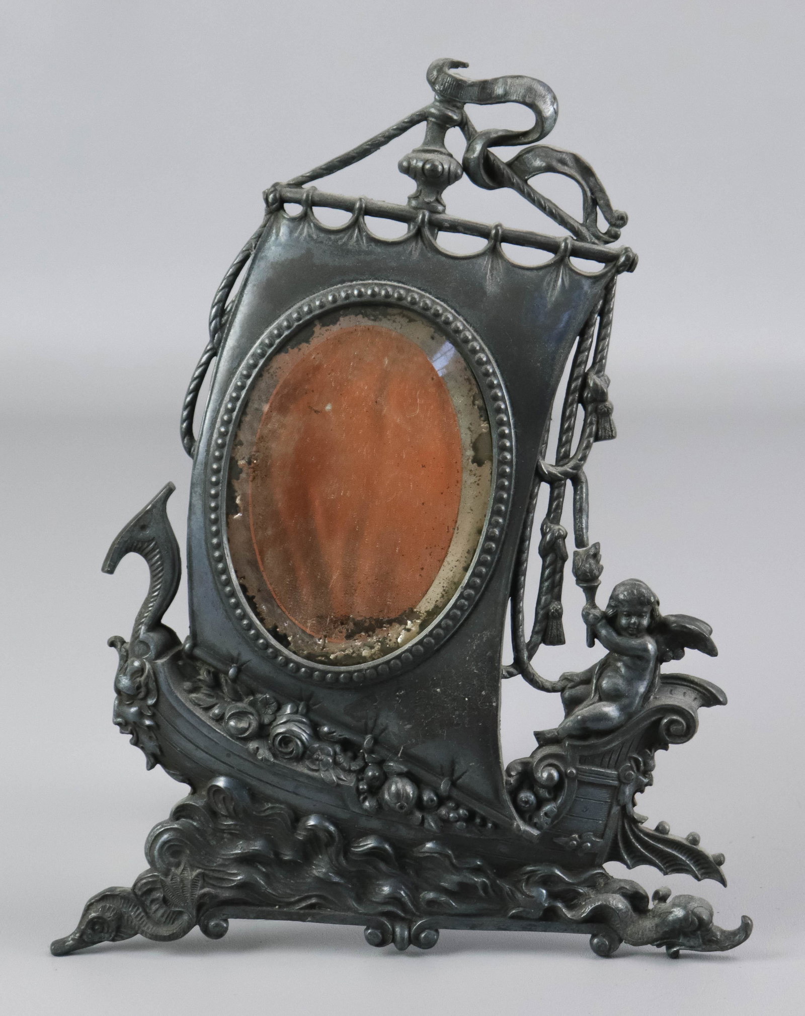 Victorian Figural Angel Sailed Ship Framed Mirror: Victorian figural angel sailed ship framed mirror, depicting angel with torch, holding sail line, driving sail ship through aesthetic waters, mirror at center, 13" x 10-1/4", missing stand.
