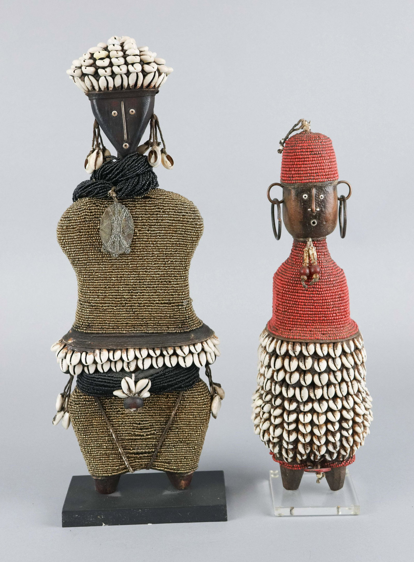 (2) African Najmi Cowrie Shell Beaded Dolls: (2) African carved wood Najmi dolls, cowrie shell, beads & Kente cloth decoration, used as both fertility dolls and play dolls, tallest 19-1/2"